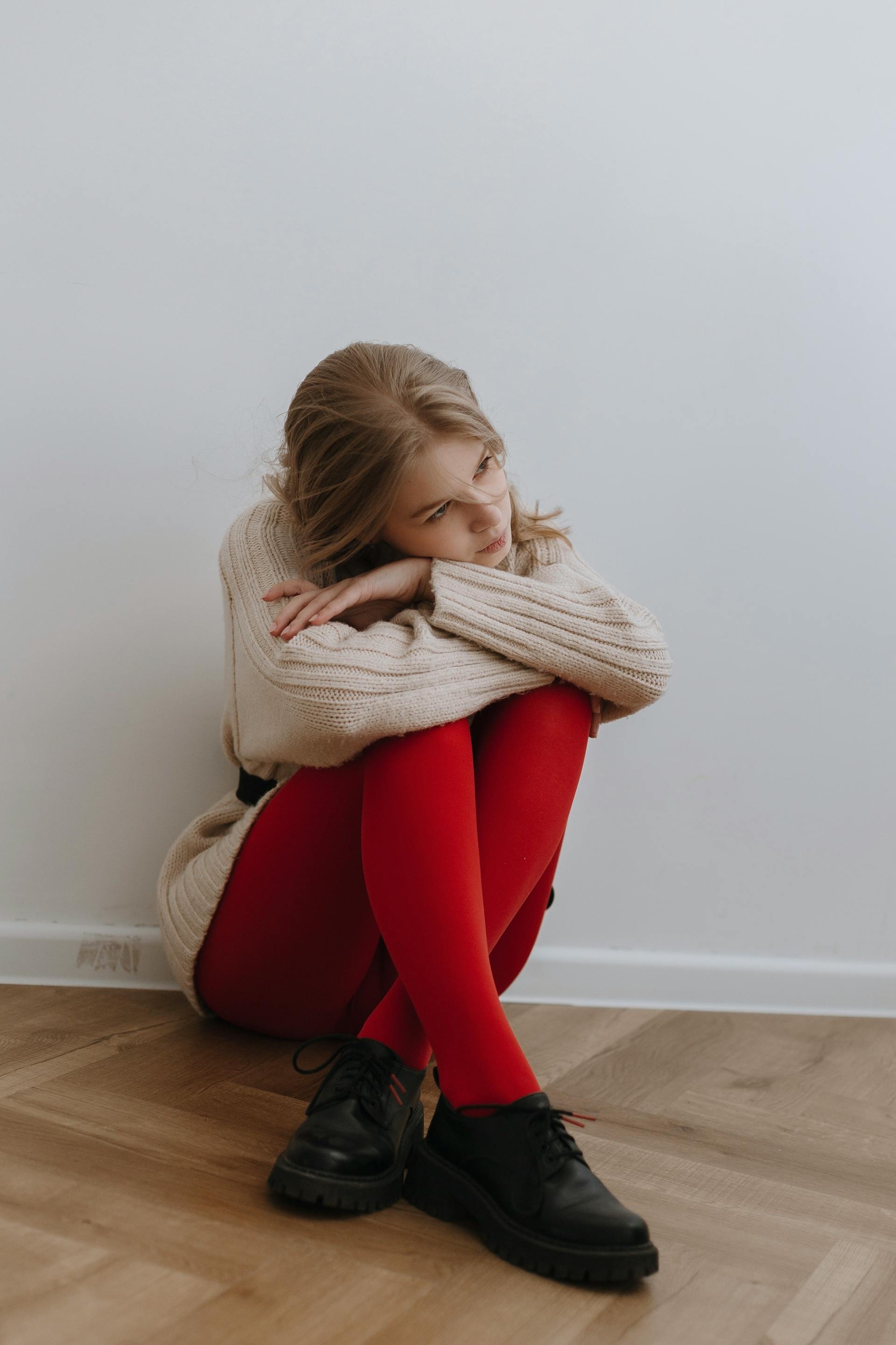 Una mujer cansada sentada en el suelo junto a una pared | Fuente: Pexels