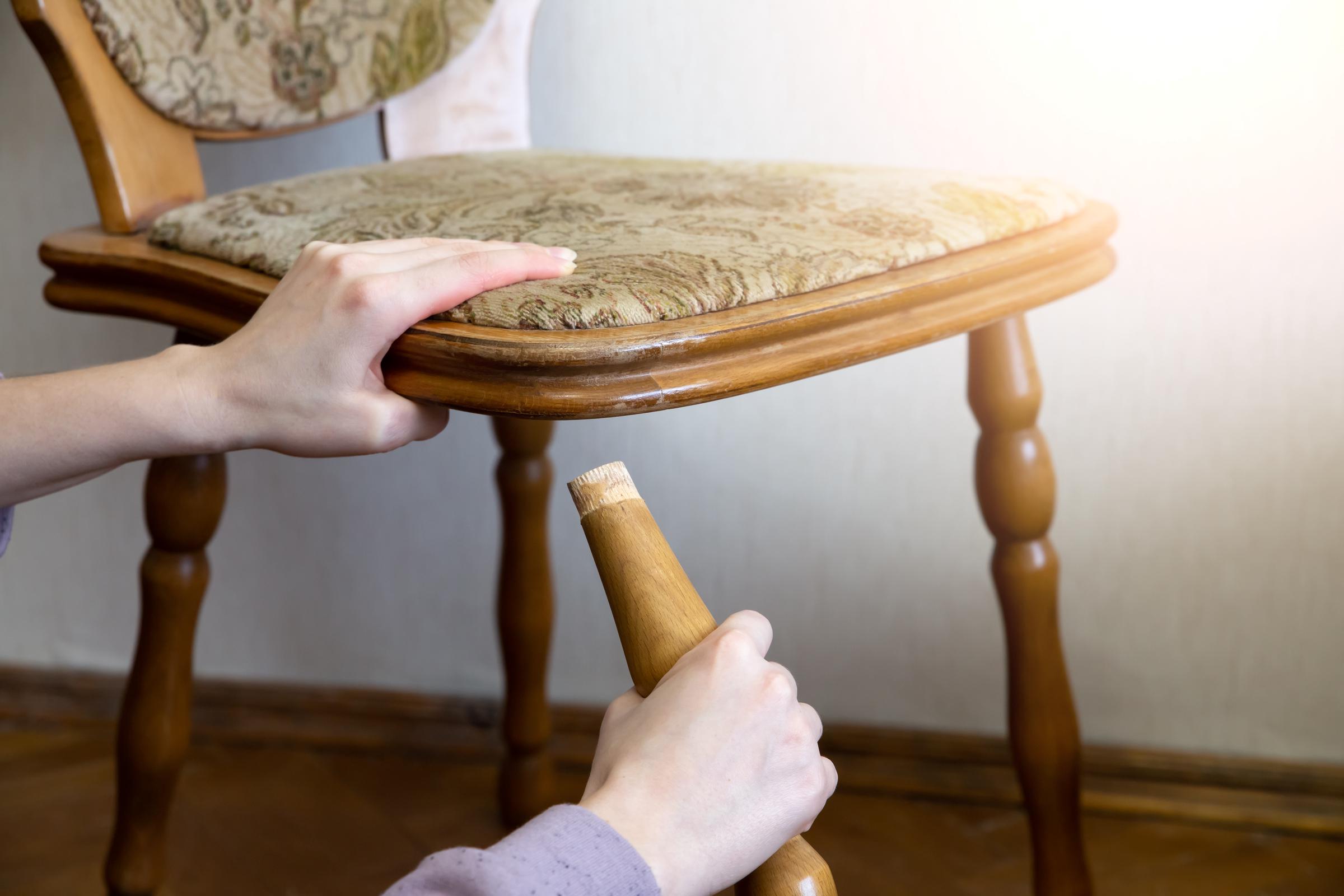 Primer plano de una mujer sujetando la pata de una silla rota | Fuente: Shutterstock