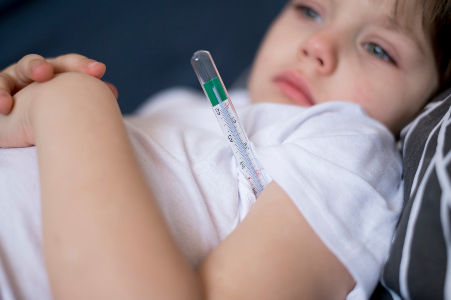 Primer plano de un niño enfermo en reposo con un termómetro | Fuente: Freepik