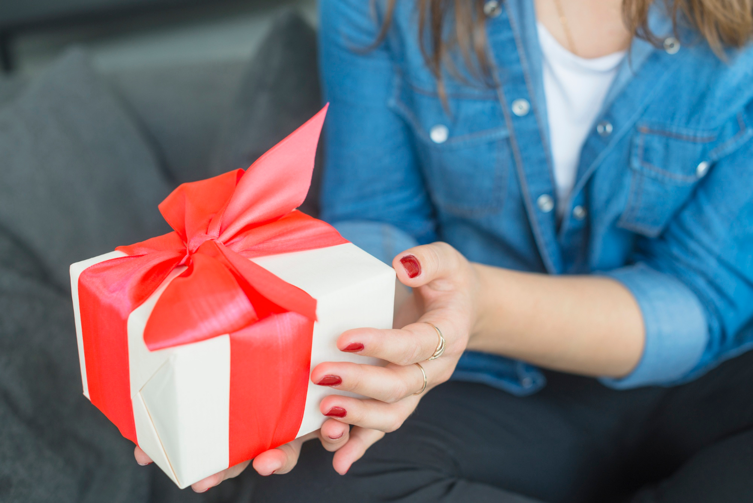 Una joven sosteniendo un regalo cuidadosamente envuelto y adornado con un brillante lazo rojo | Fuente: Freepik