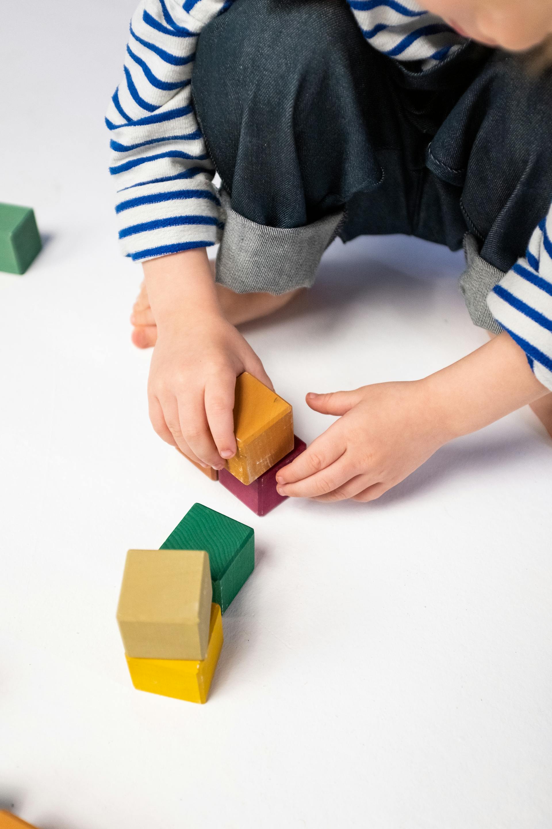 Primer plano de un niño jugando con bloques de plástico | Fuente: Pexels