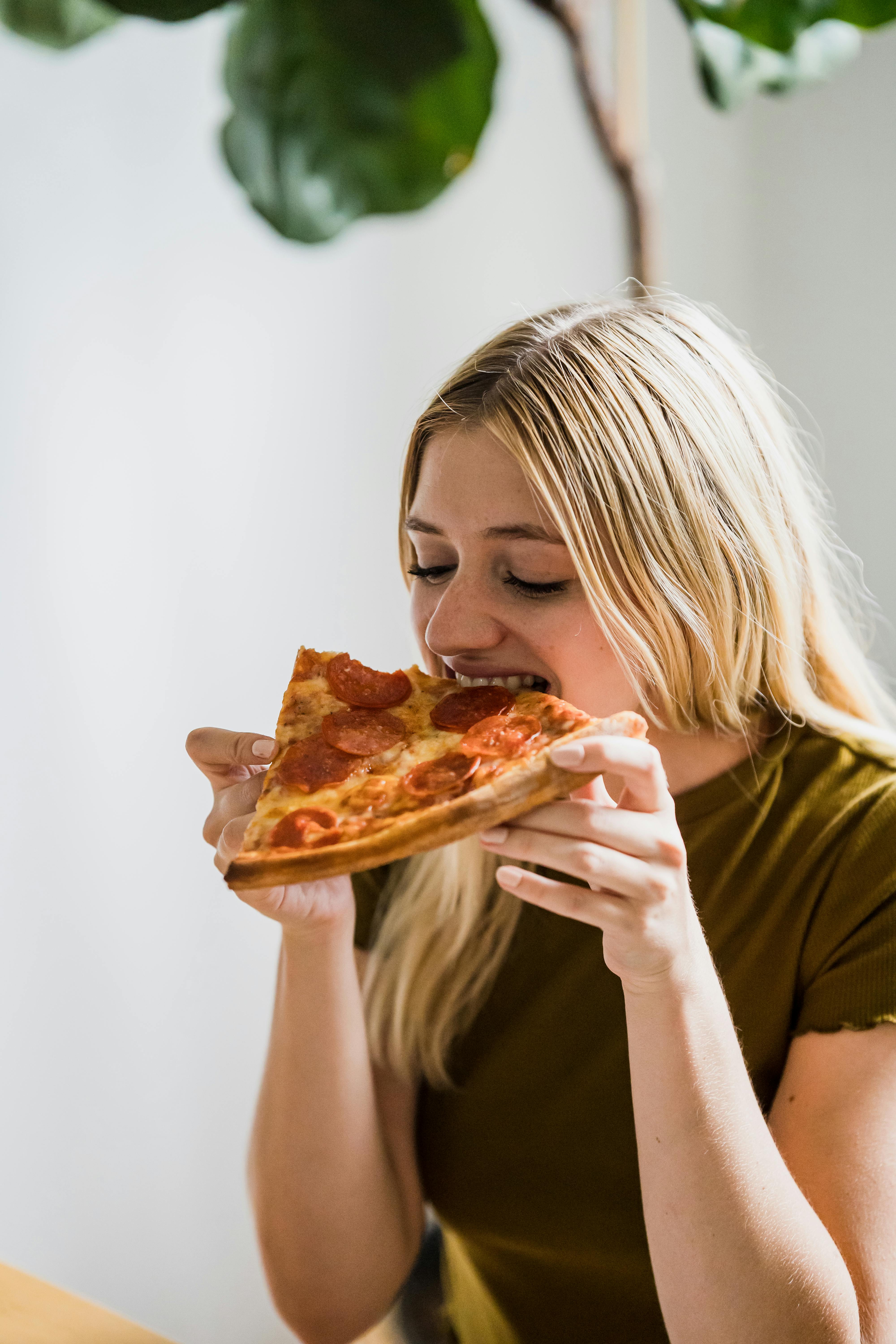 Una mujer feliz comiendo pizza | Fuente: Pexels