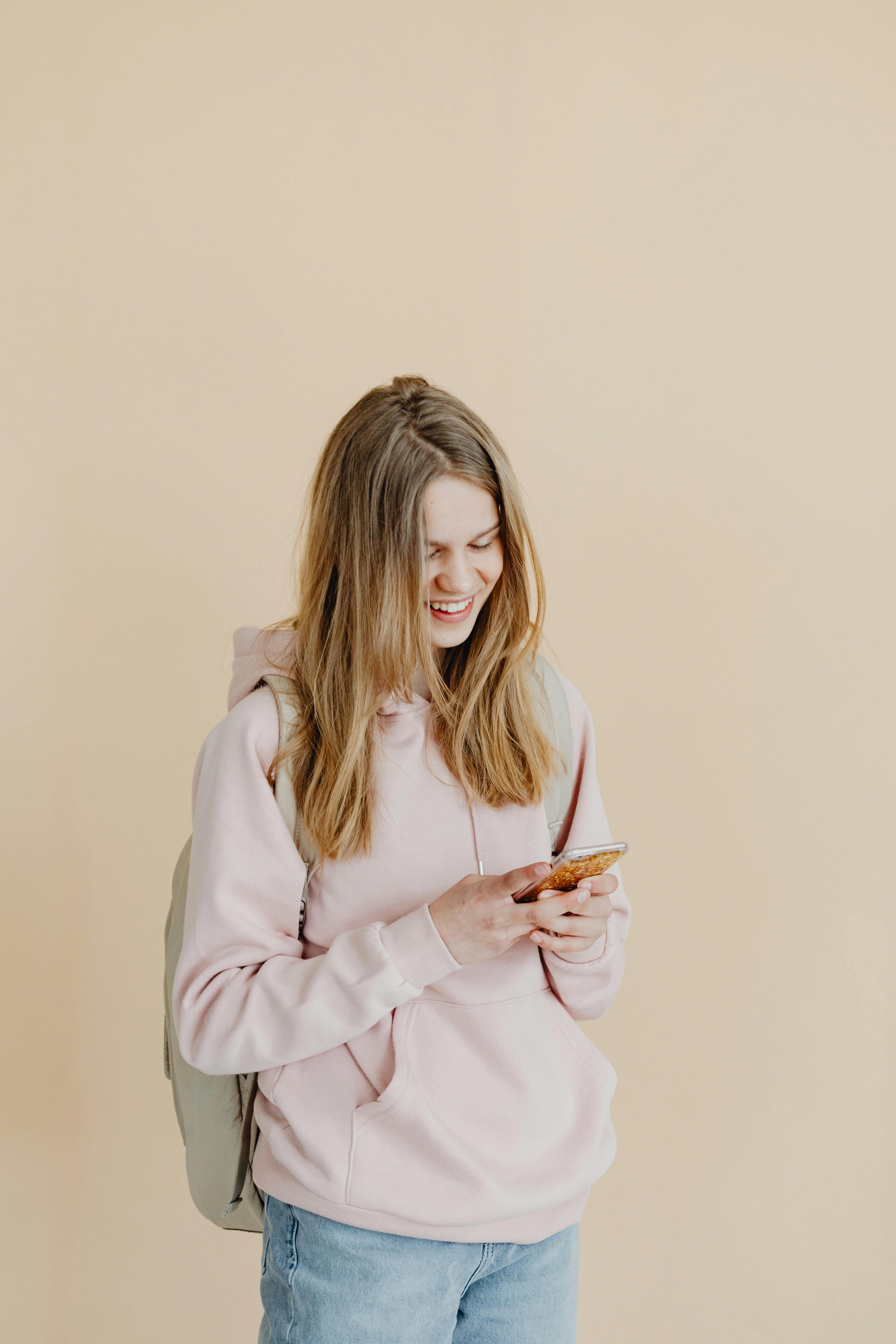 Una chica feliz mirando su teléfono | Fuente: Pexels