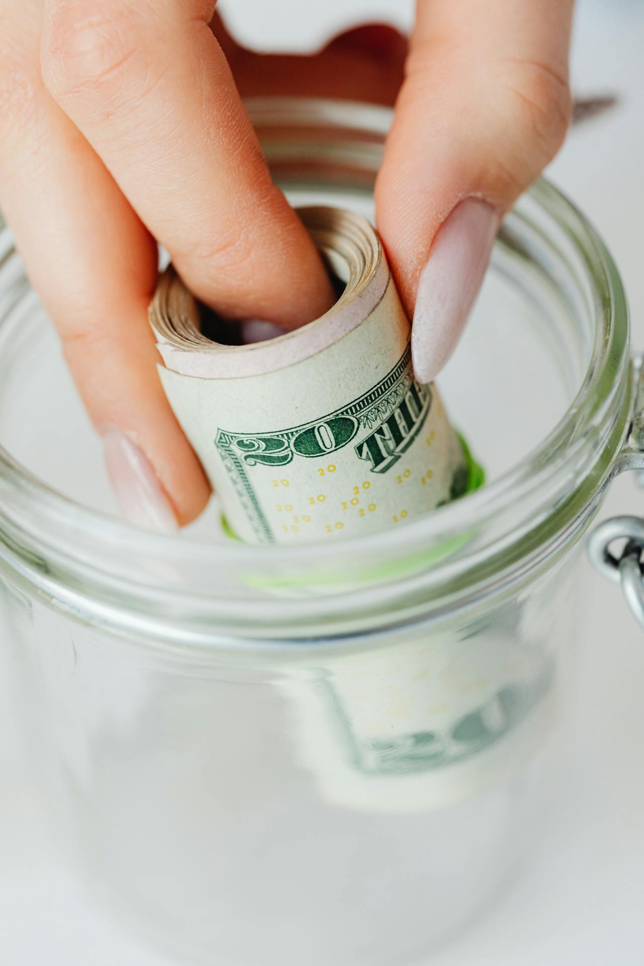Una mujer poniendo billetes enrollados en un tarro de cristal | Fuente: Pexels