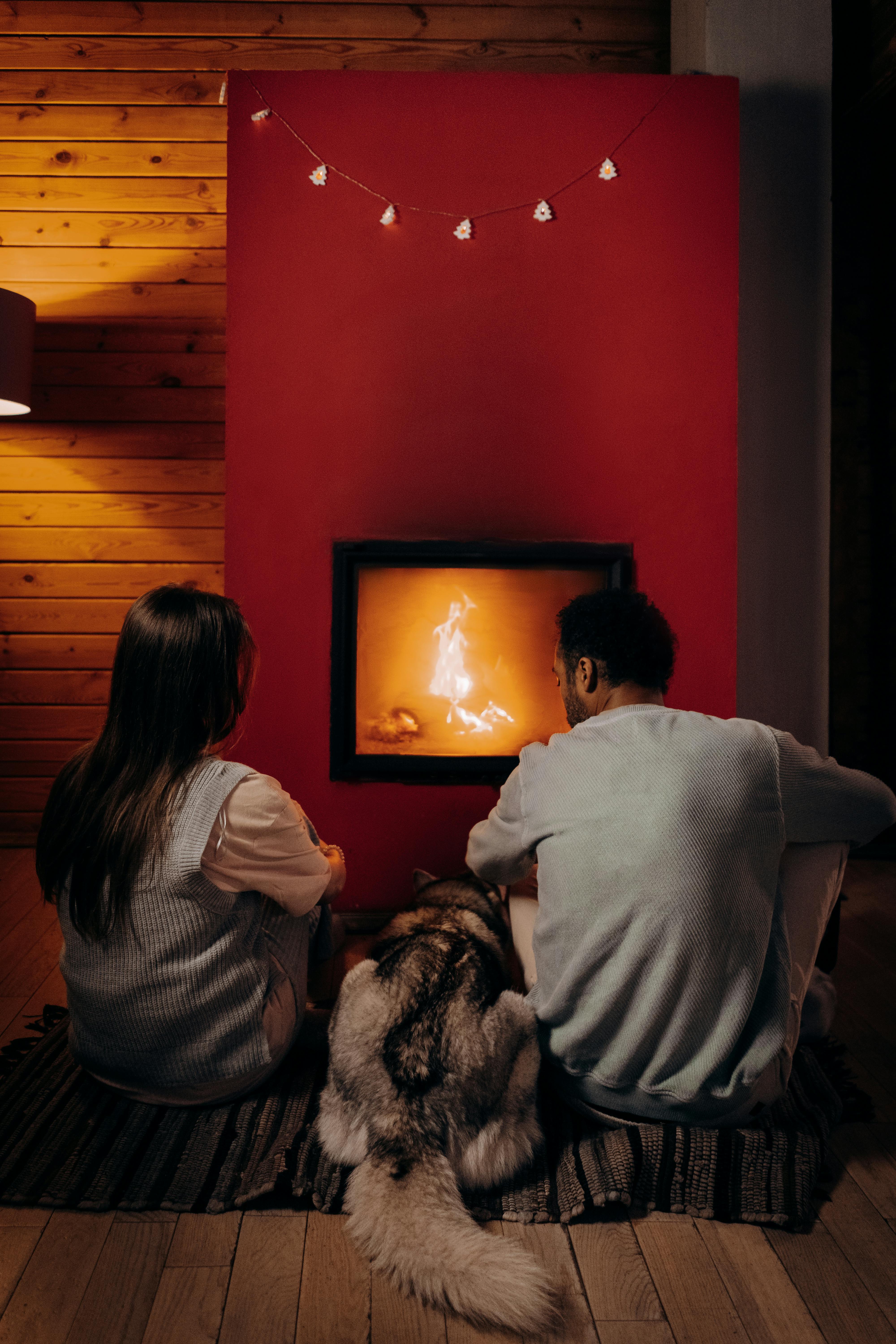 Una pareja sentada cerca de una chimenea con su perro | Fuente: Pexels