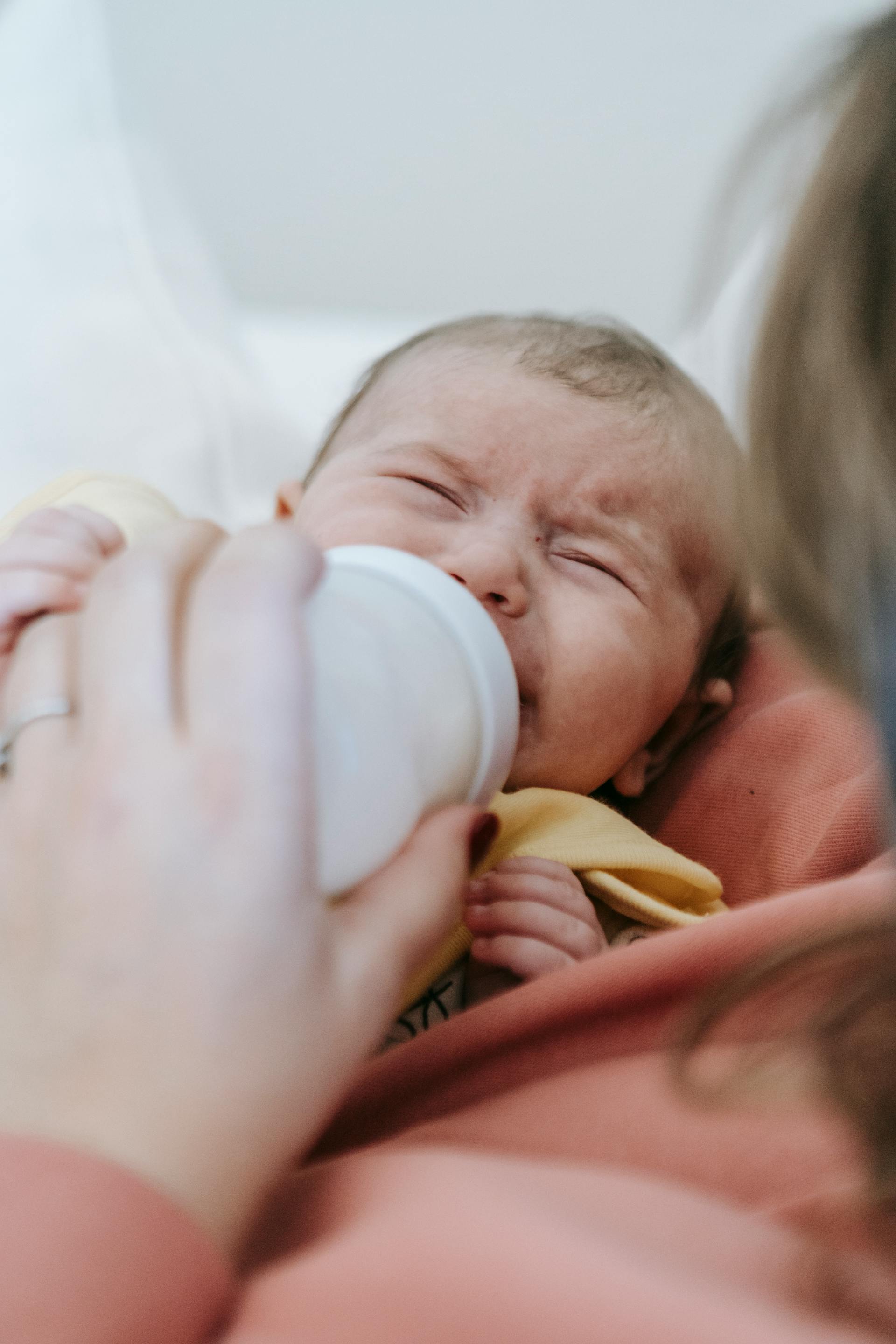 Una mujer dando de comer a un bebé que llora | Fuente: Pexels
