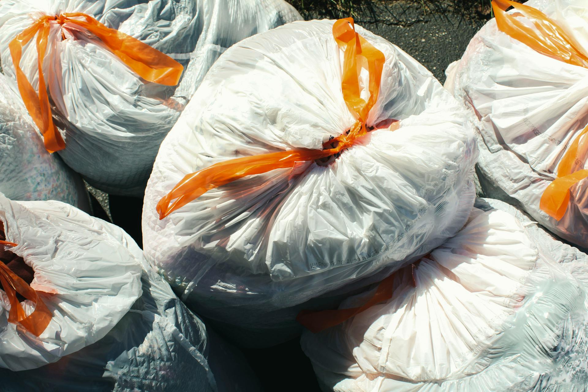 Varias bolsas de basura atadas con una cinta naranja | Fuente: Pexels