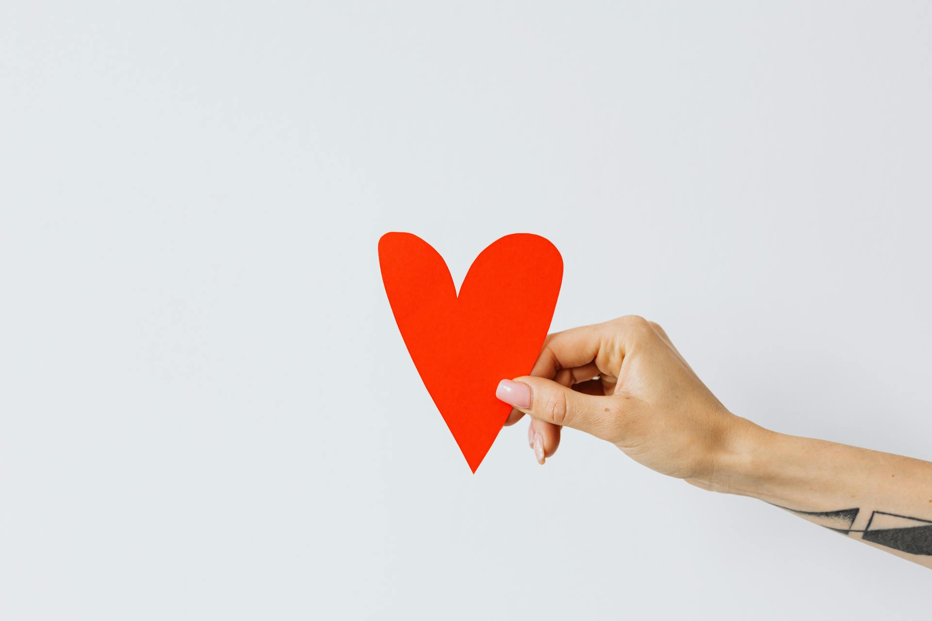Una mujer con un corazón de papel rojo | Fuente: Pexels