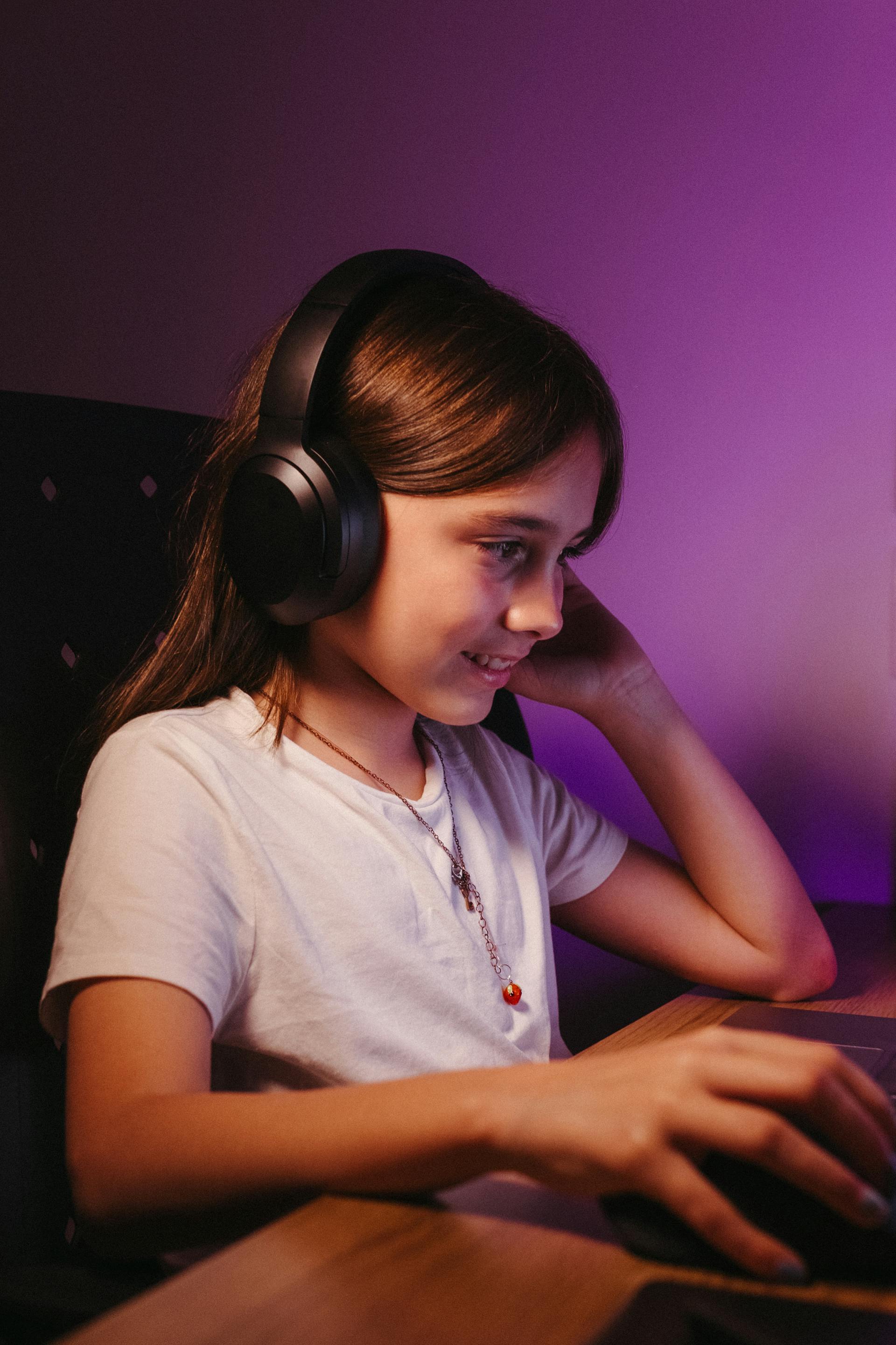 Una adolescente utilizando unos auriculares y un ordenador | Fuente: Pexels
