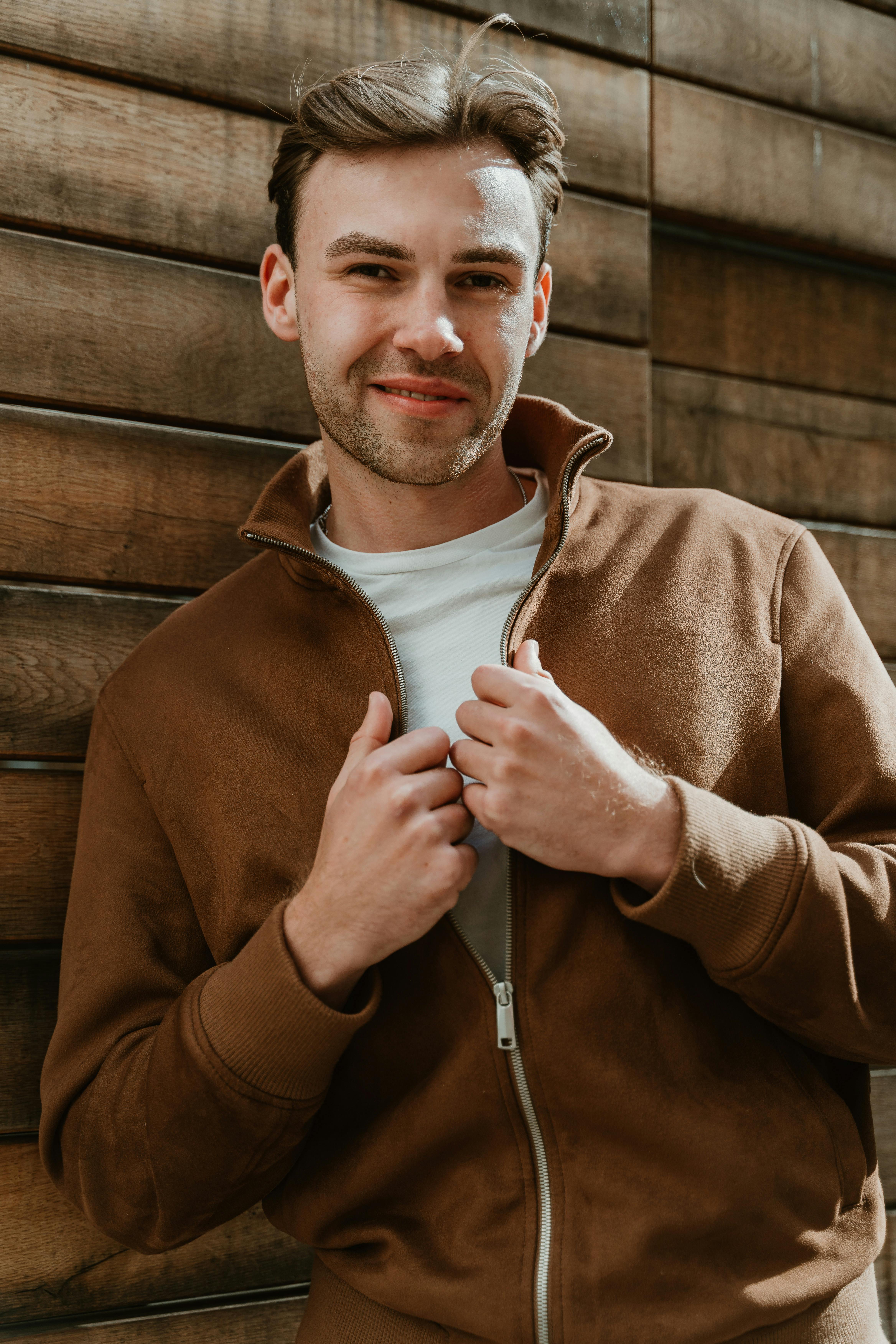 Un joven sonriente con una chaqueta marrón | Fuente: Pexels