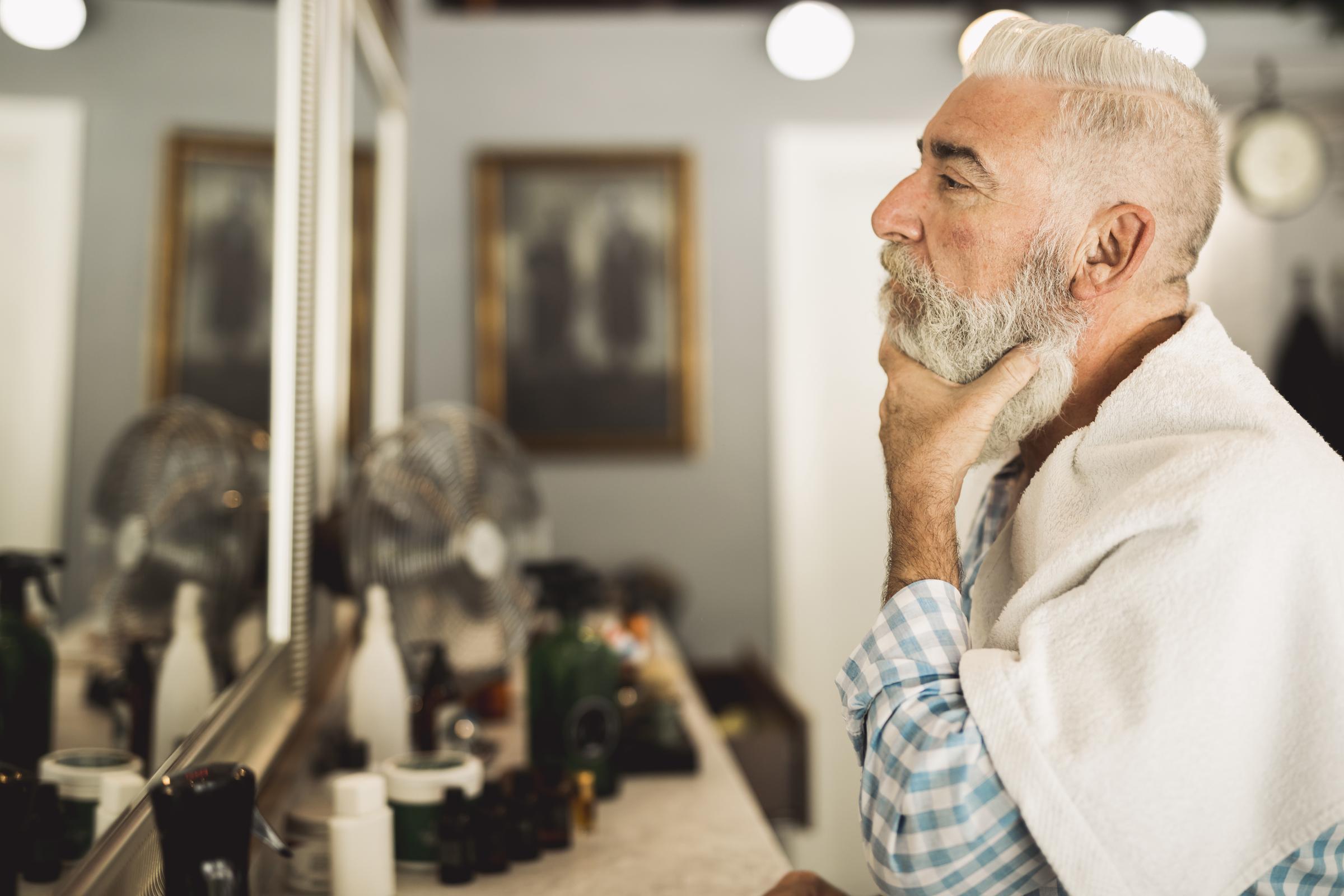 Un anciano mirándose en un espejo | Fuente: Freepik