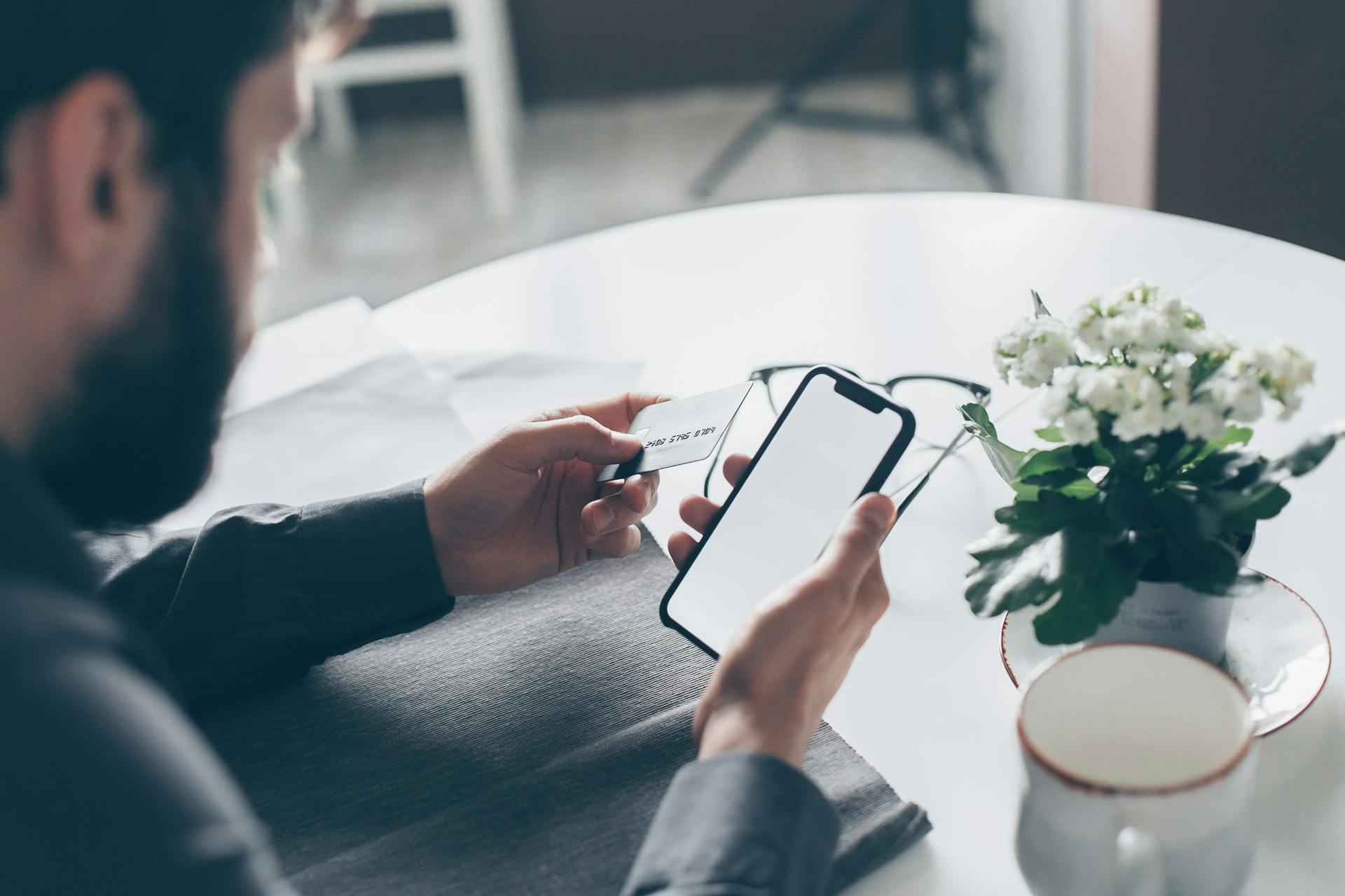 Un hombre con una tarjeta bancaria y un teléfono móvil | Fuente: Pexels