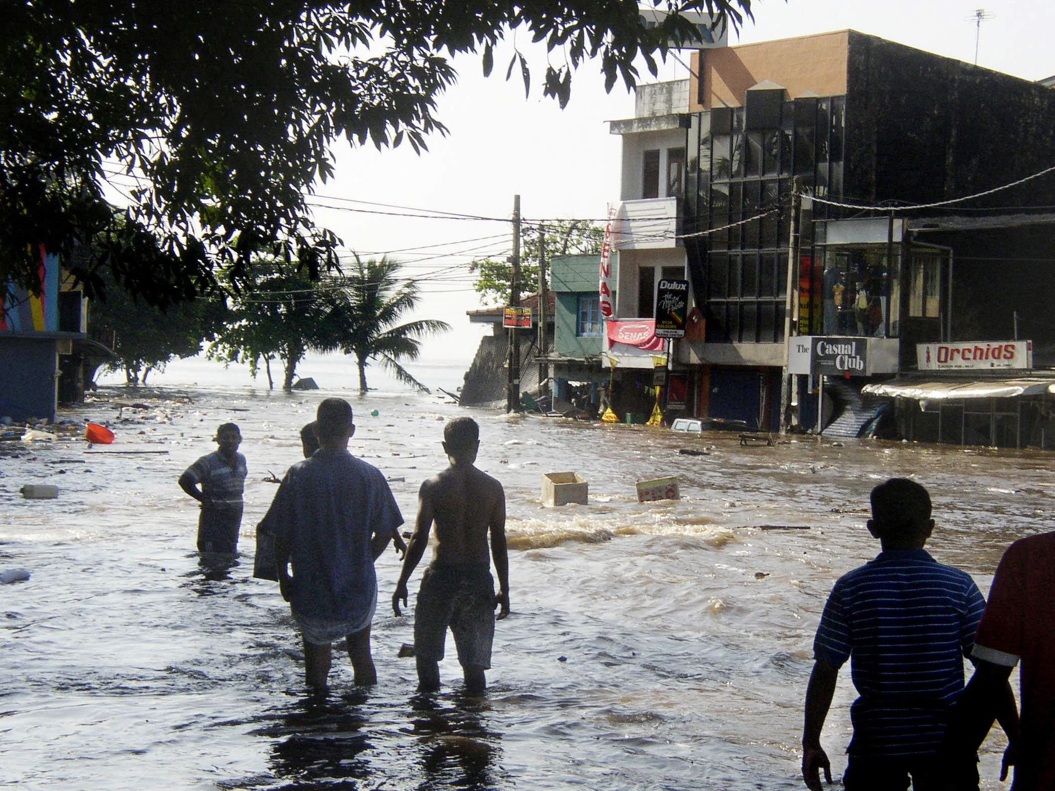 En esta fotografía, tomada el 26 de diciembre de 2004, peatones de Sri Lanka caminan entre las aguas en una calle principal de Galle, después de que la ciudad costera fuera azotada por un maremoto. | Fuente: Getty Images