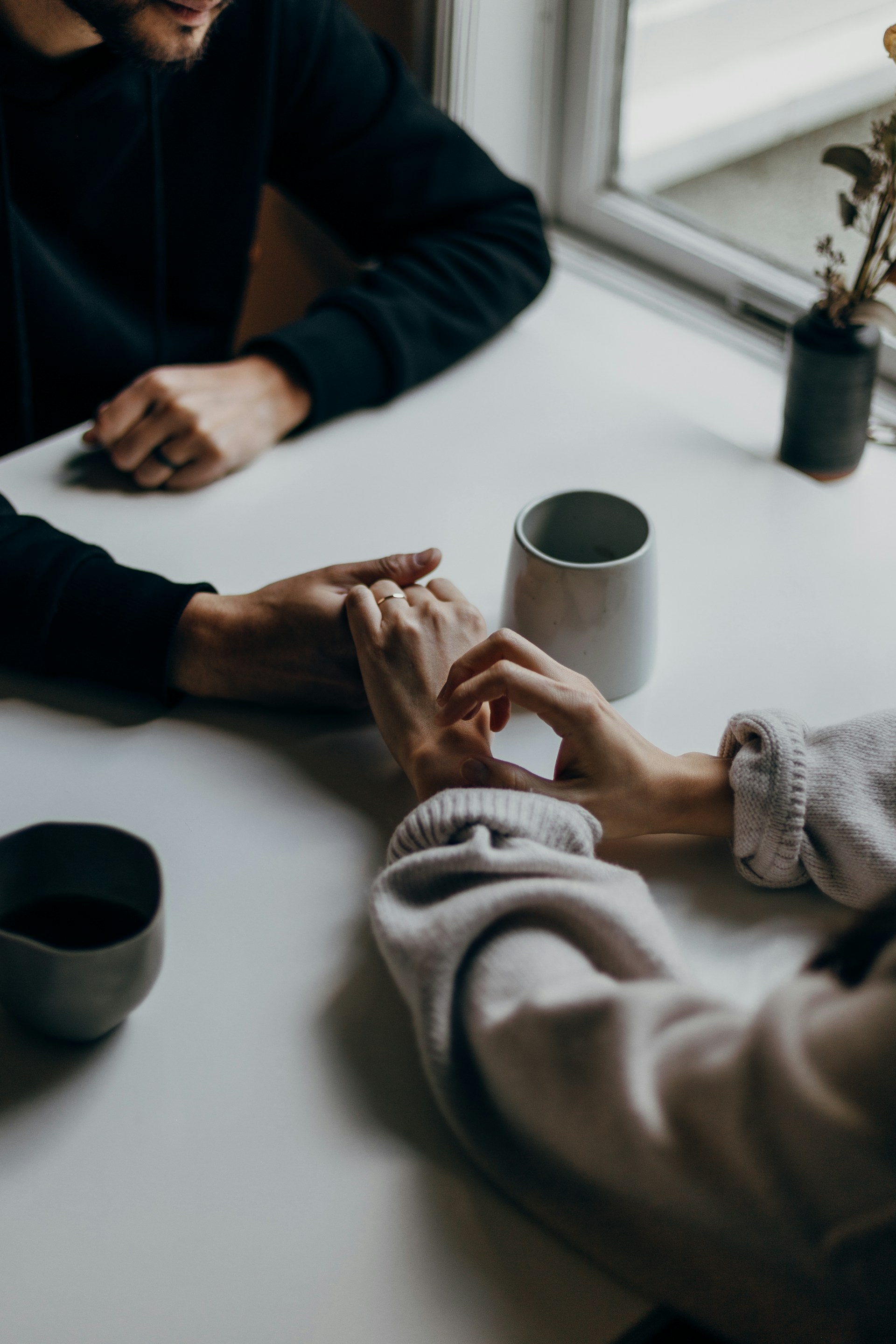 Una pareja tomada de la mano a través de una mesa | Fuente: Unsplash