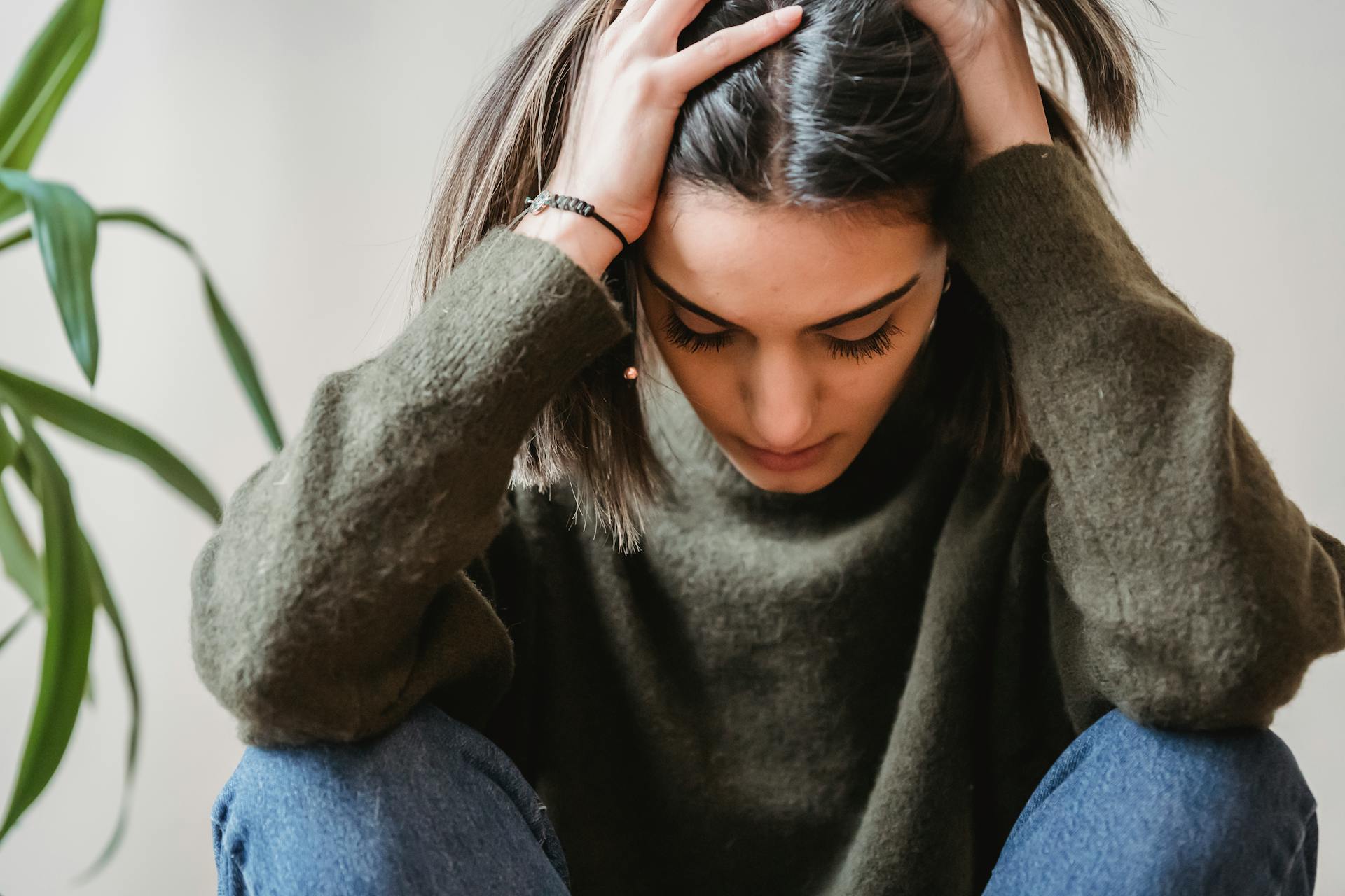 Una mujer sentada con la cabeza entre las manos | Fuente: Pexels