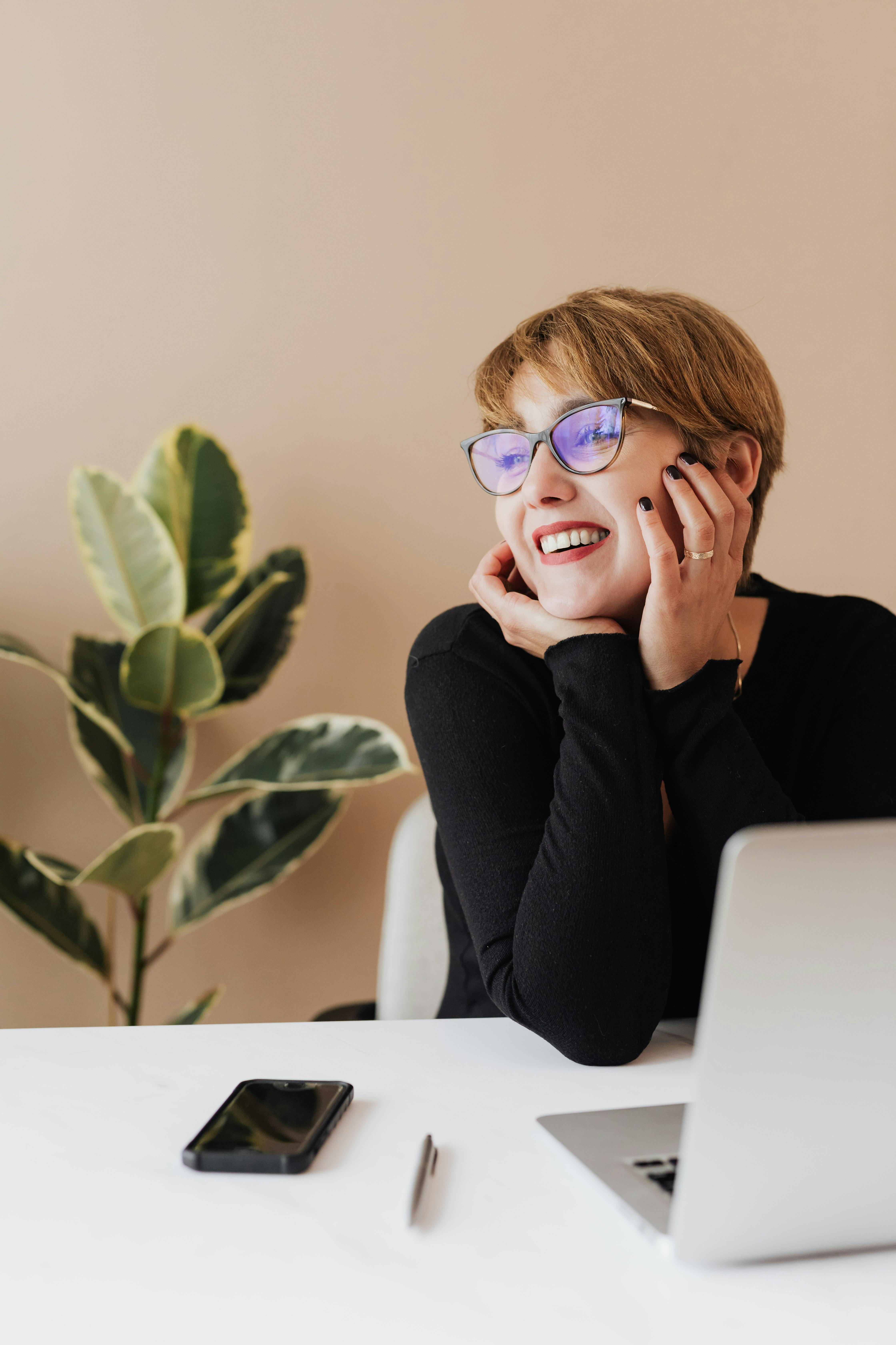 Mujer sonriendo mientras mira su portátil | Fuente: Pexels