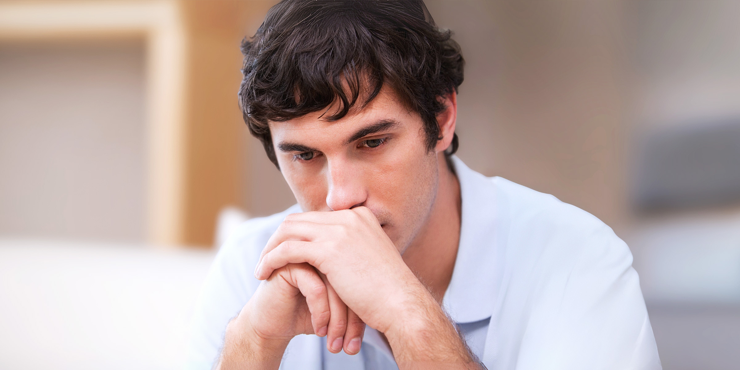 Un hombre reflexivo sentado en un salón | Fuente: Shutterstock