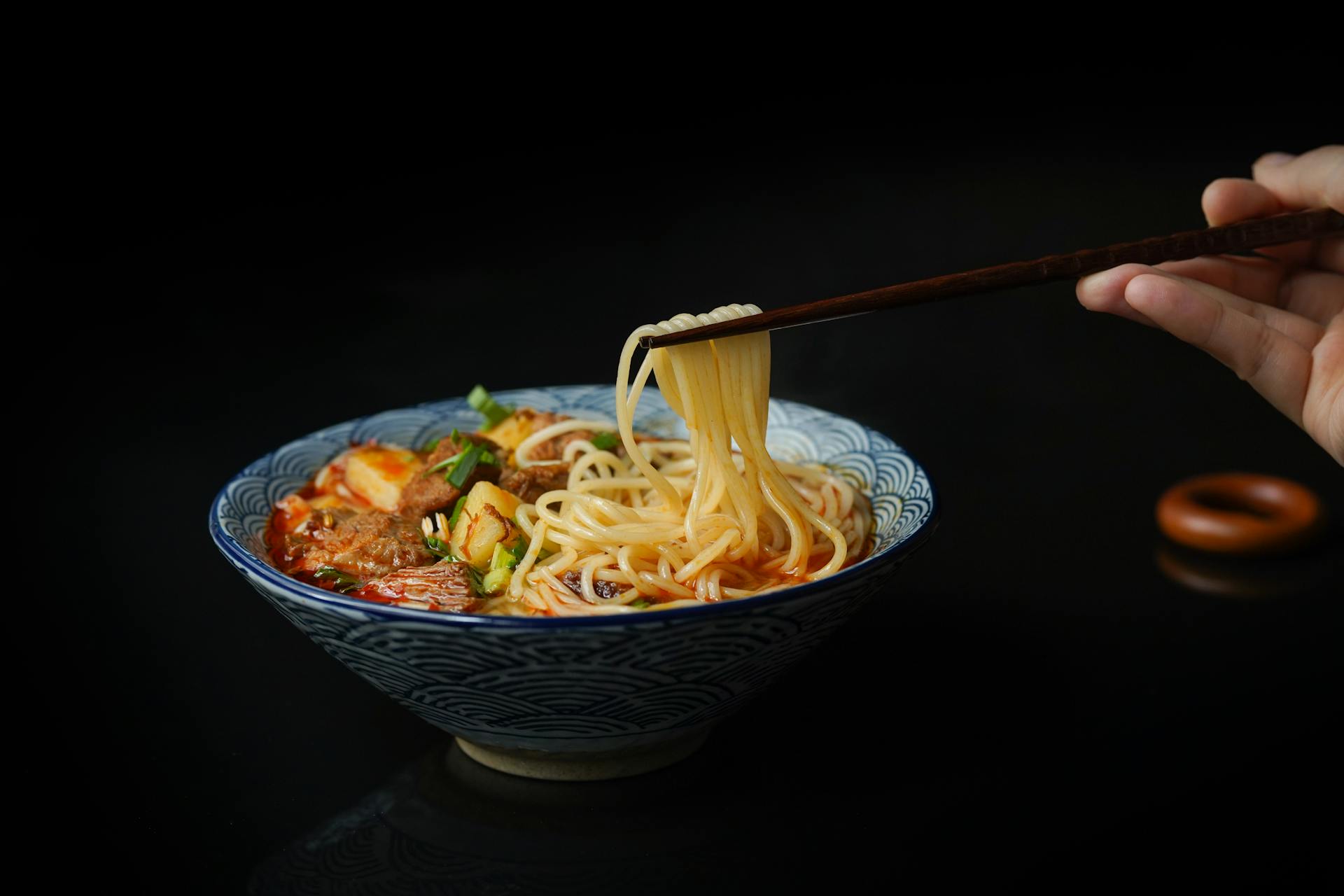Una persona sujetando fideos con palillos | Fuente: Pexels