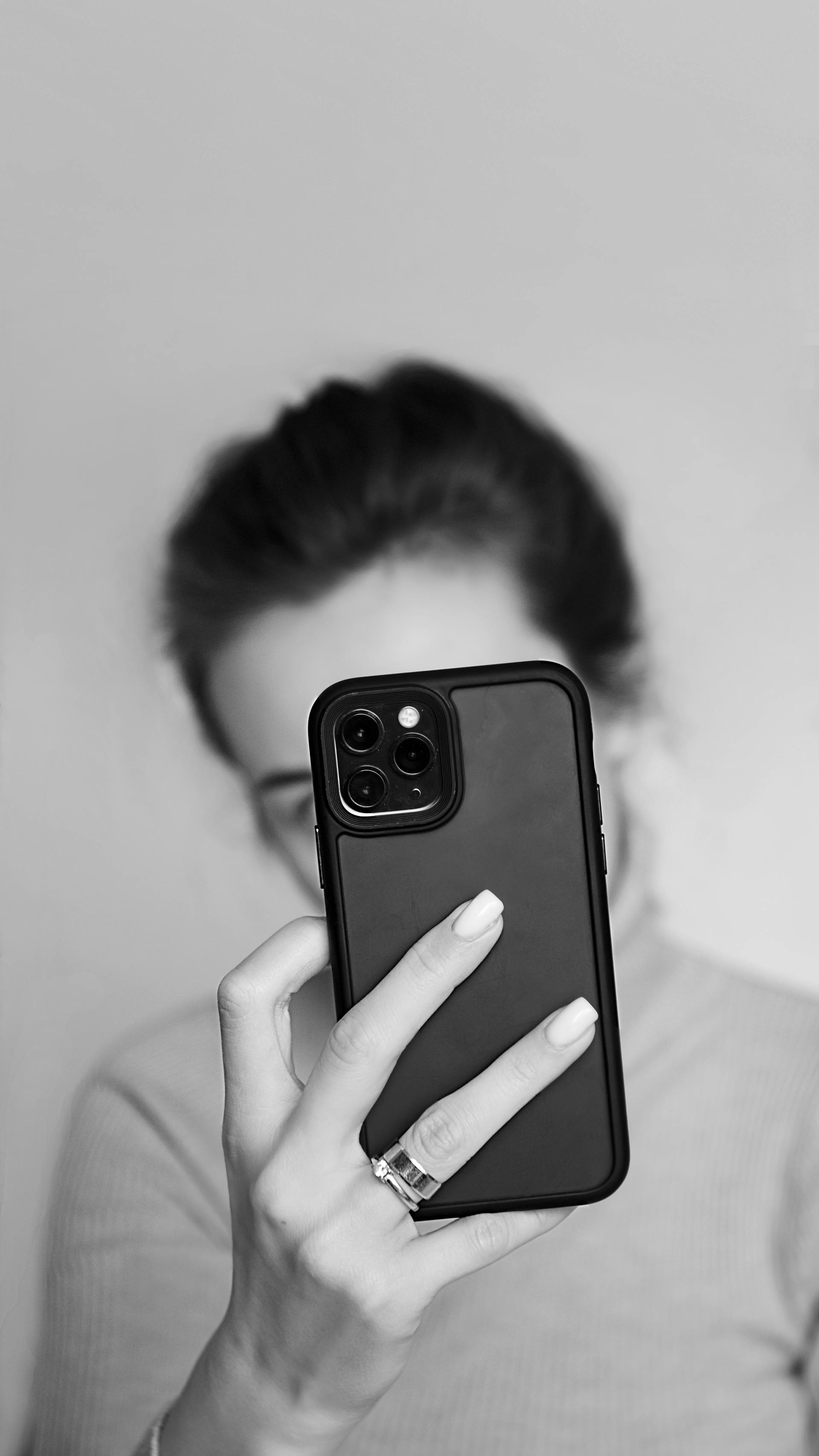 Toma en escala de grises de una mujer sujetando su teléfono | Fuente: Pexels