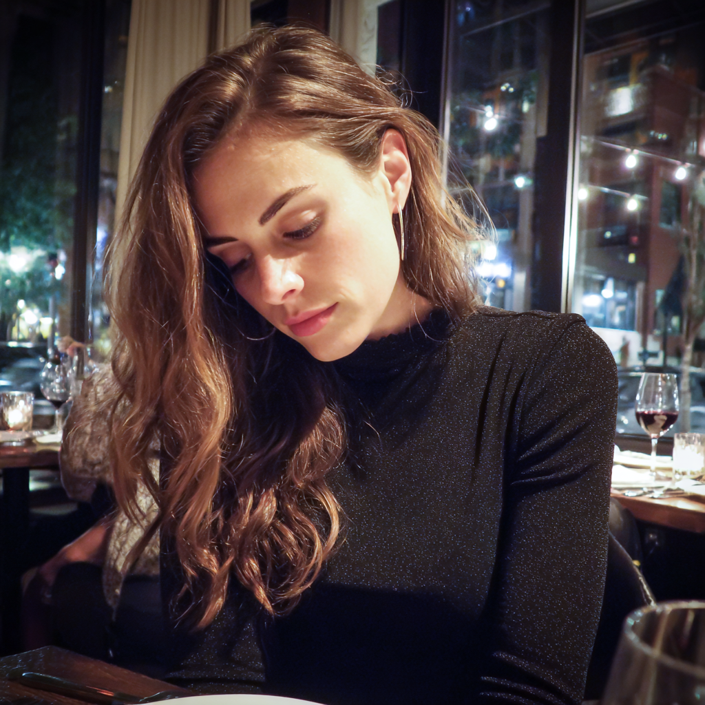 Una mujer mirando su regazo en un restaurante | Fuente: Midjourney