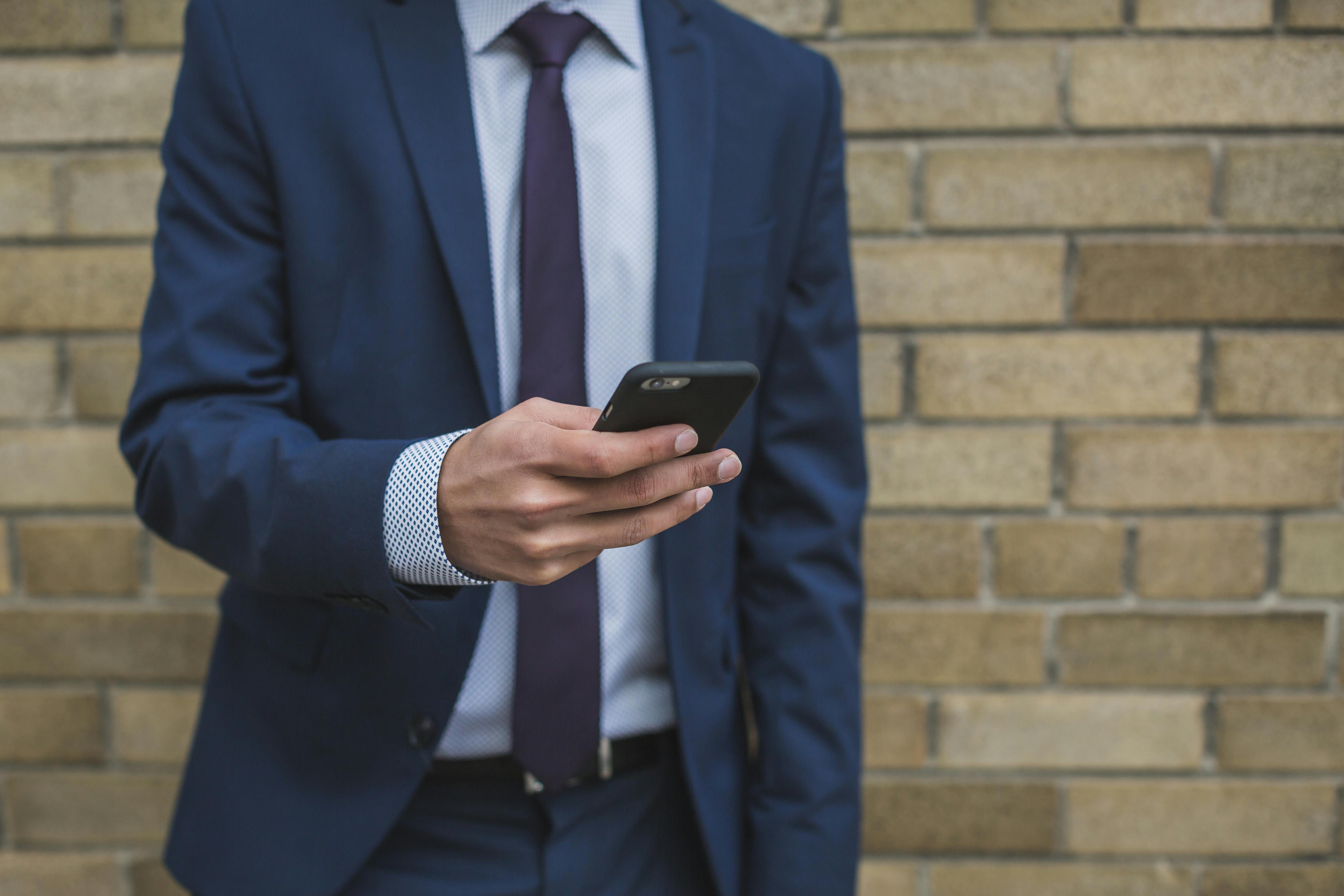 Hombre trajeado usando su smartphone | Fuente: Pexels