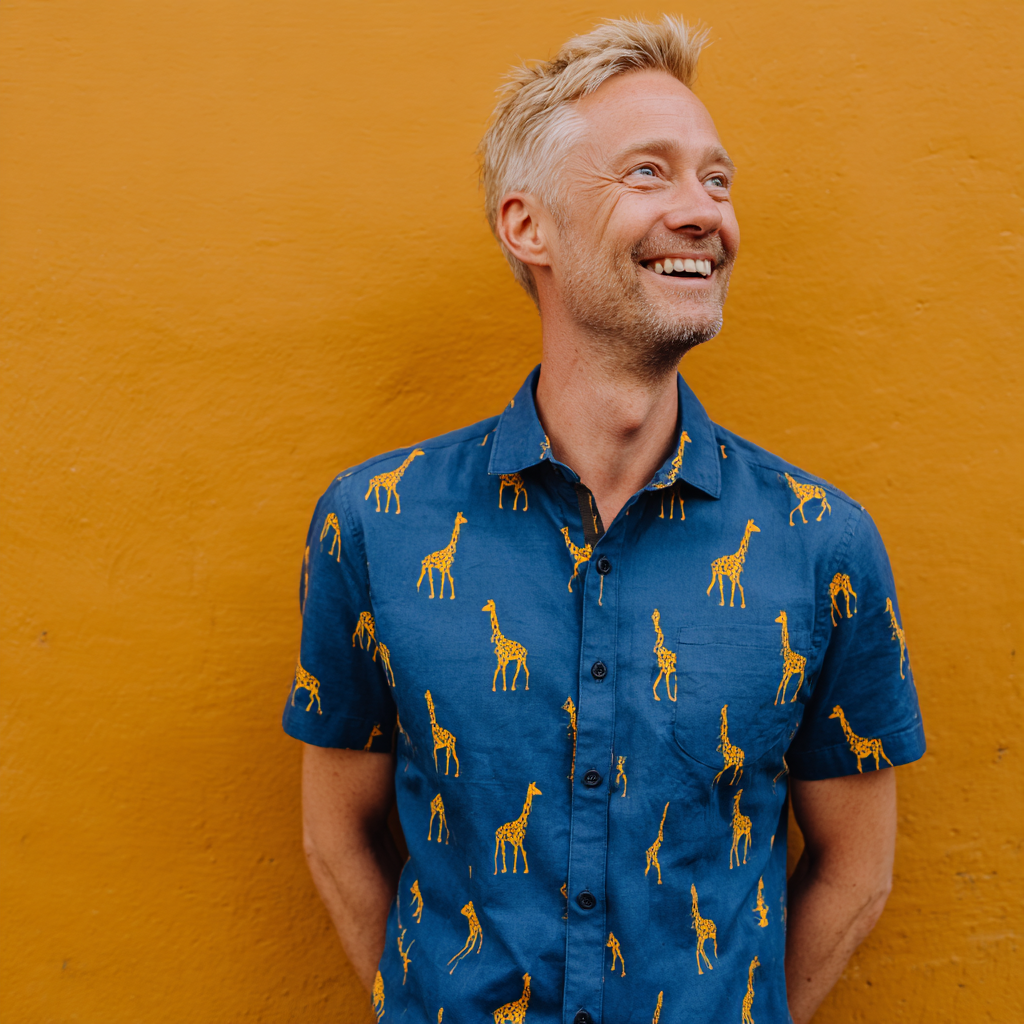 Un hombre sonriente con una camiseta estampada con una jirafa | Fuente: Midjourney