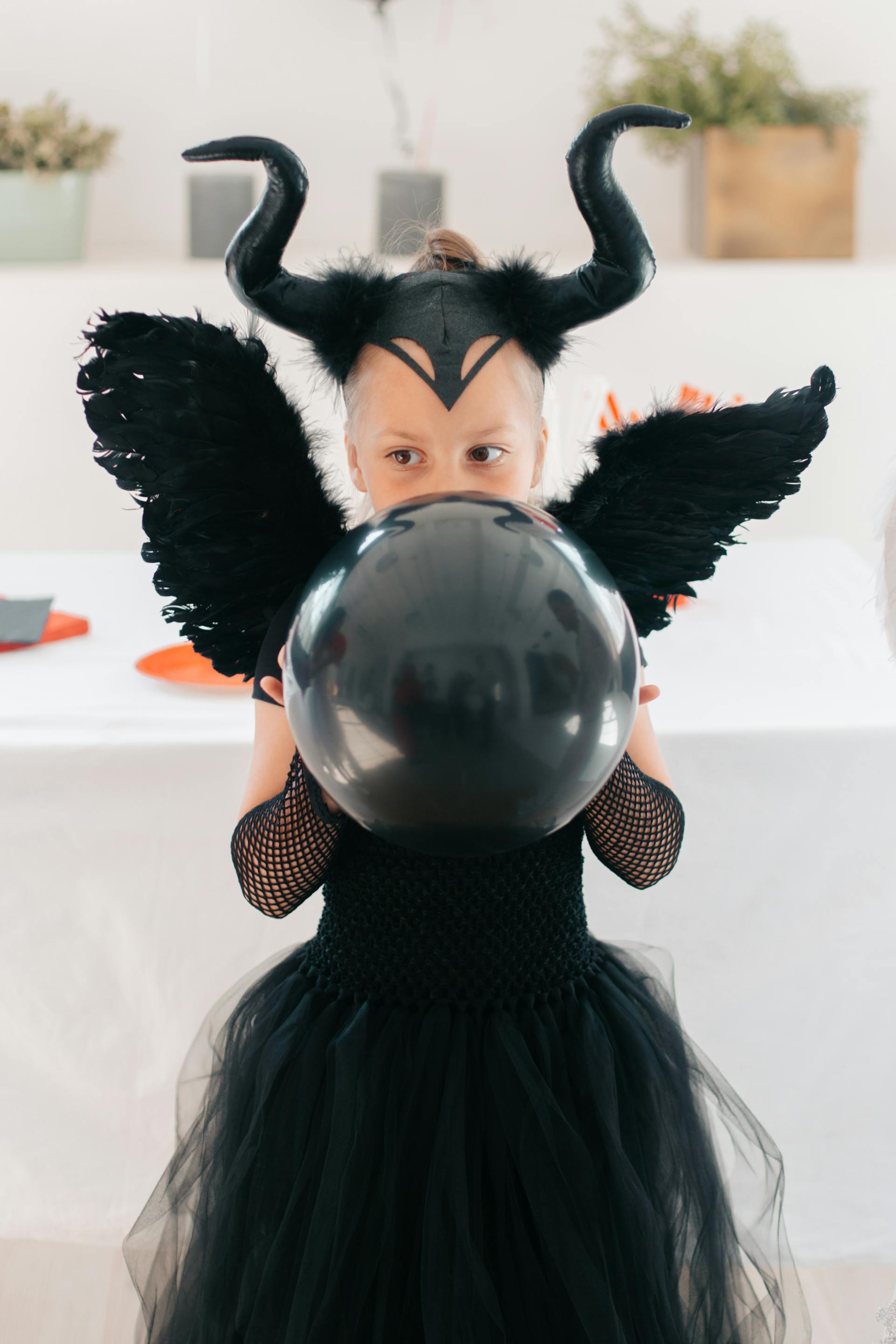 Una joven con un disfraz negro de Halloween y un globo en la mano | Fuente: Pexels