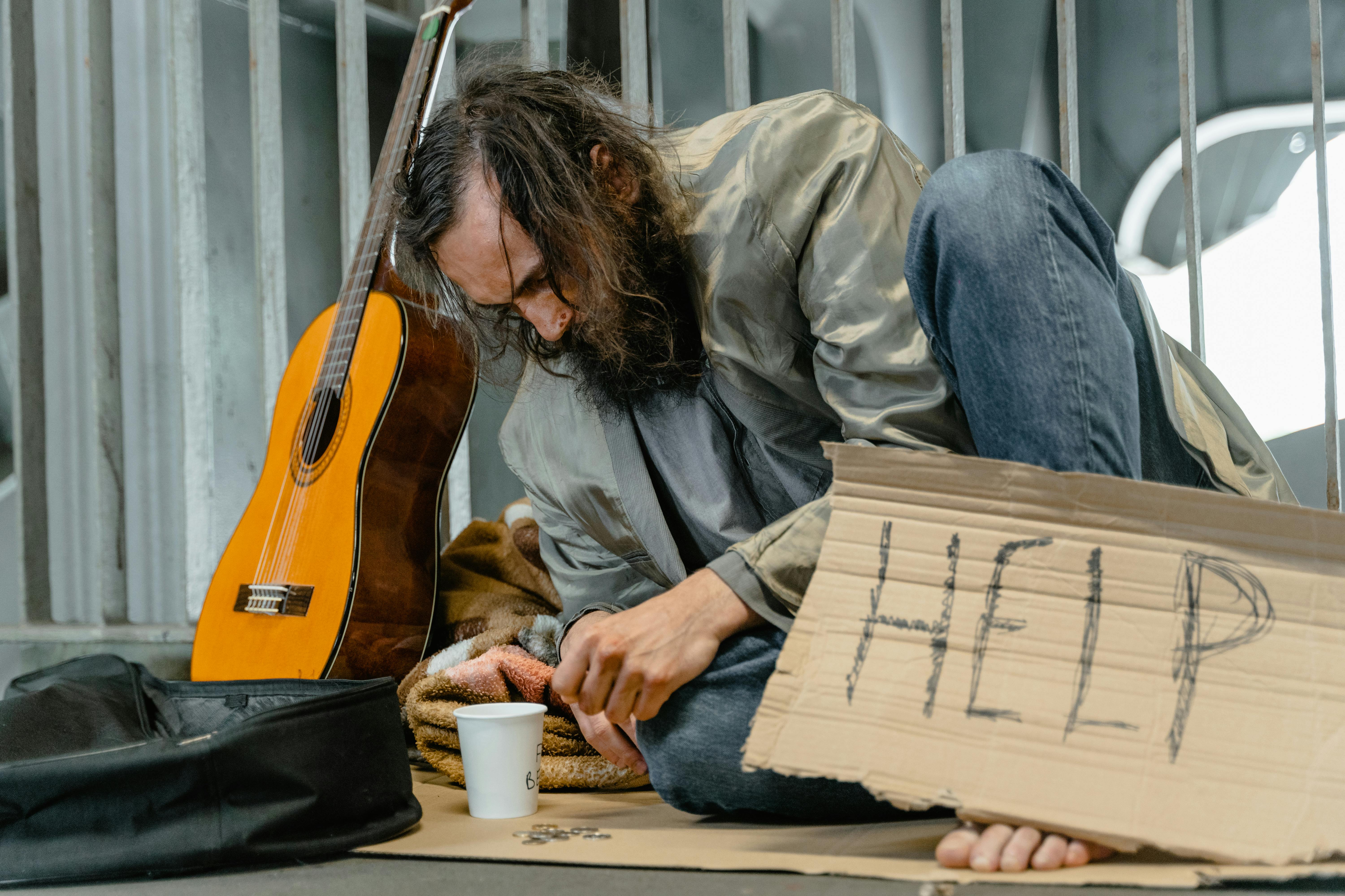 Hombre sin hogar con un cartel | Fuente: Pexels