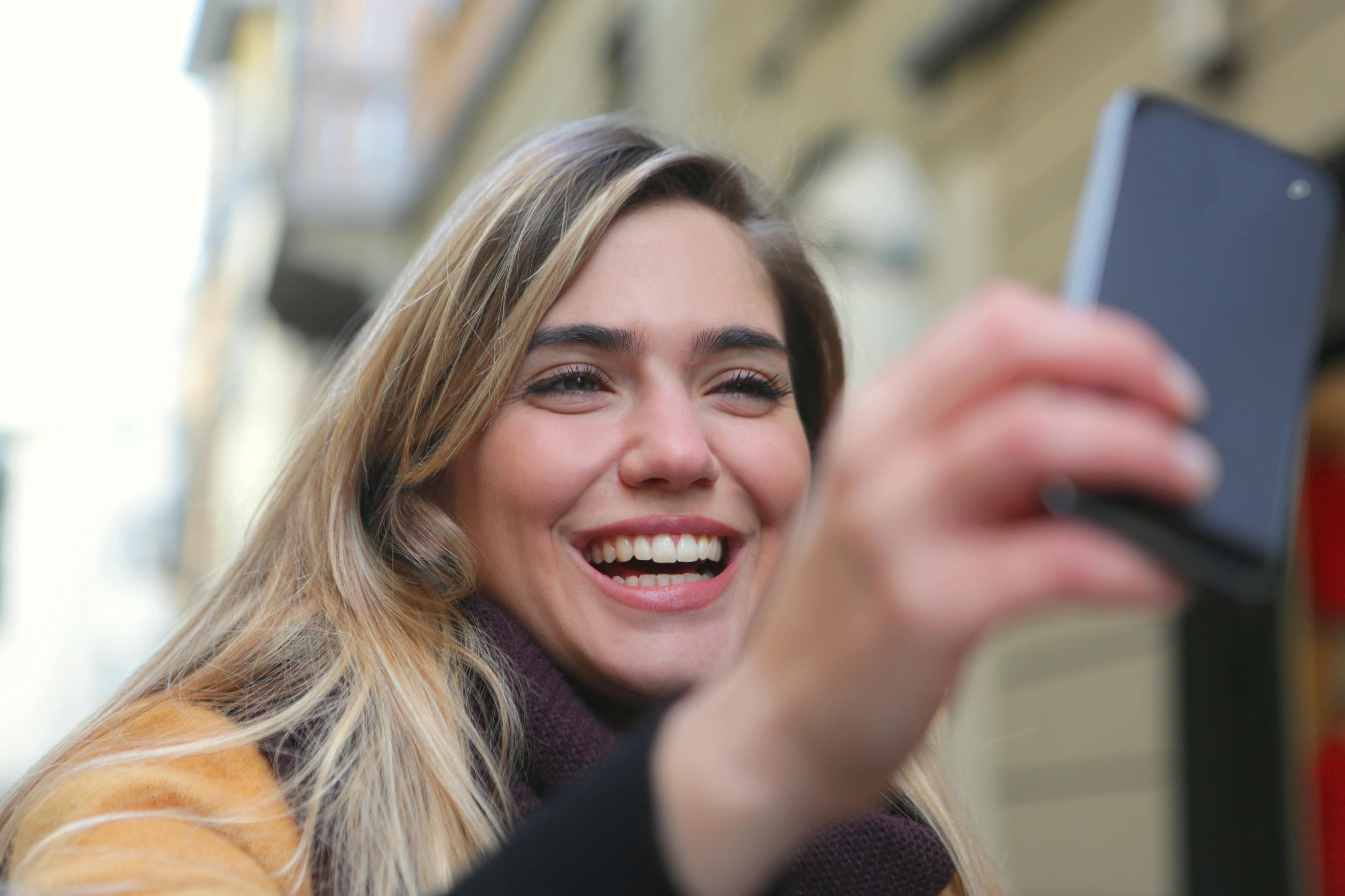 Una mujer feliz usando su teléfono | Fuente: Pexels
