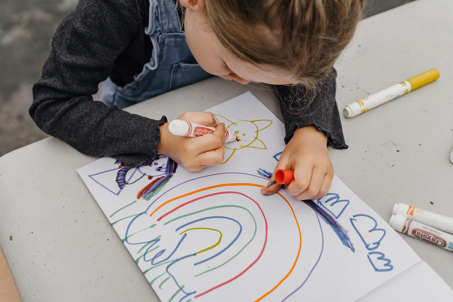Primer plano de una niña dibujando con rotuladores sobre un papel | Fuente: Pexels