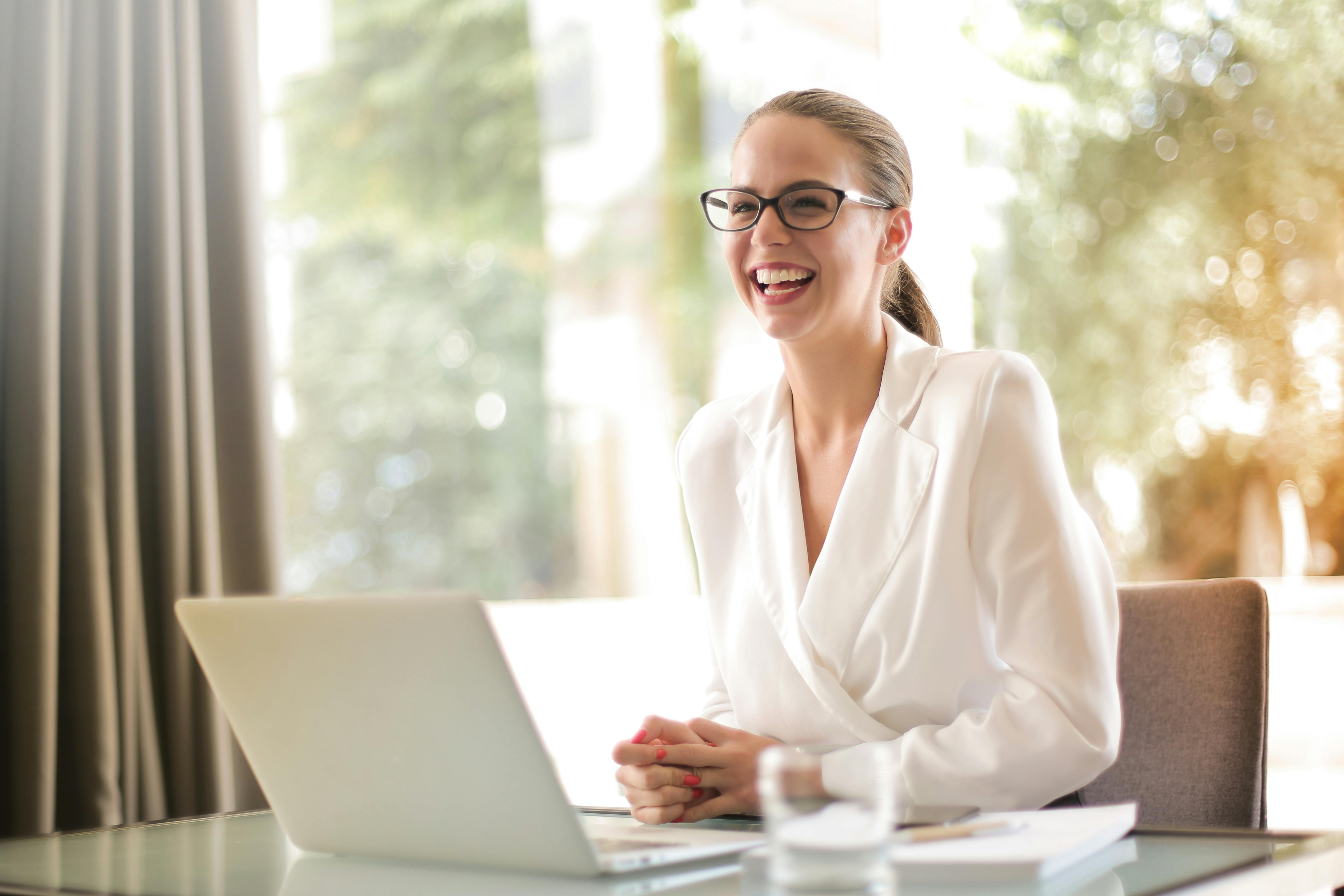 Una mujer feliz en su oficina | Fuente: Pexels