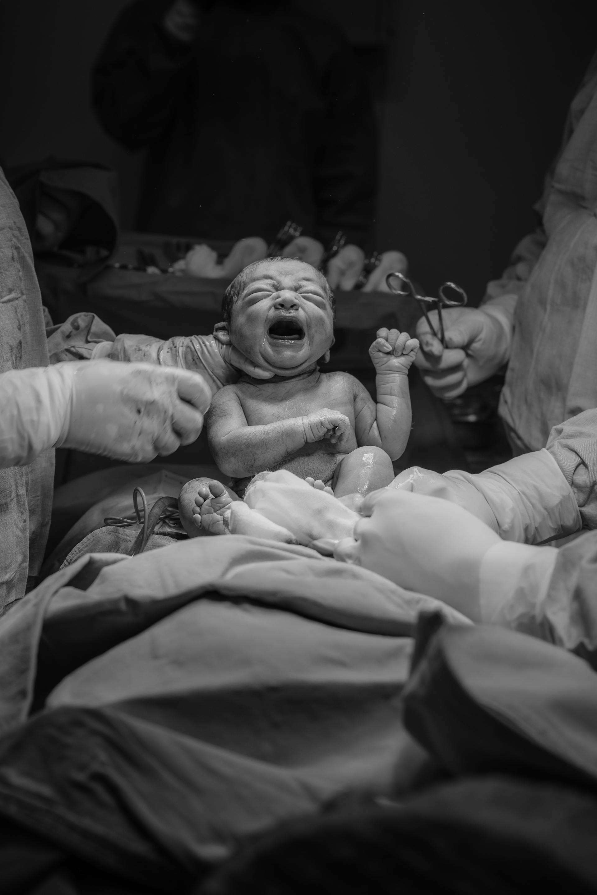 Una foto en escala de grises del personal de un hospital sujetando a un recién nacido | Fuente: Pexels