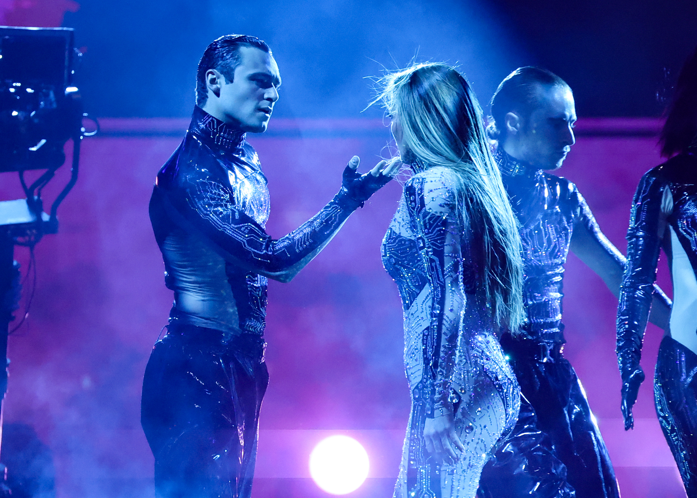 En un feroz e íntimo cara a cara, Jennifer Lopez y un bailarín mantienen una poderosa pose bajo una neblina azul, convirtiendo su presentación en los American Music Awards 2025 en Fontainebleau Las Vegas en una fusión teatral de danza, tensión y espectáculo.