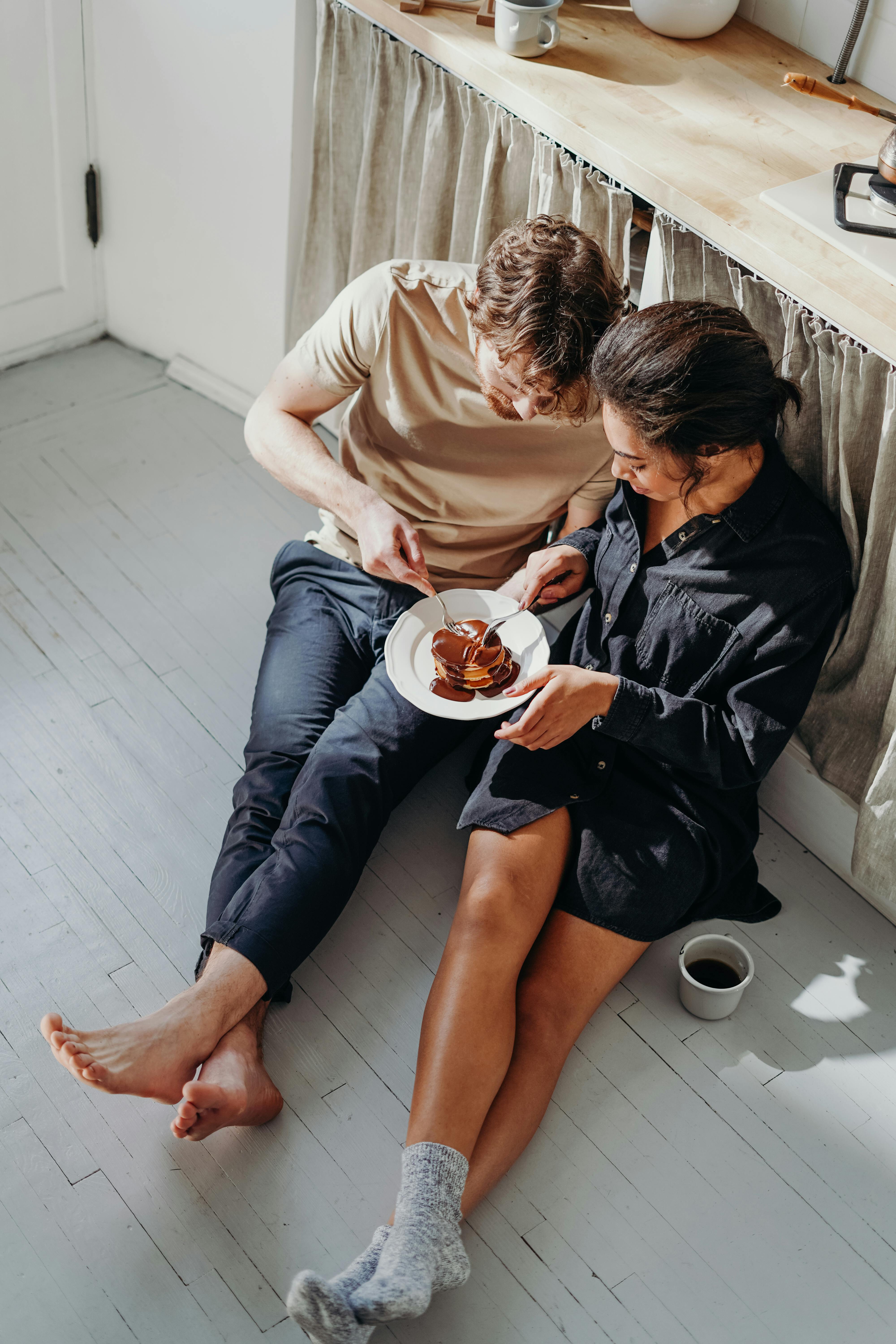 Una pareja comiendo sentada en el suelo | Fuente: Pexels