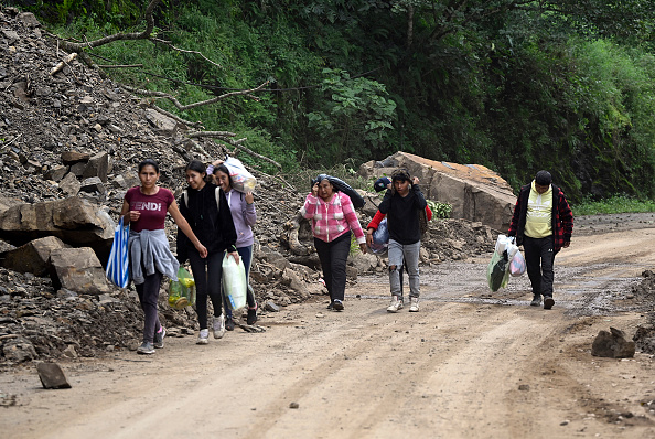Lugareños caminan por la carretera Tenango de Doria–San Bartolo Tututepec después de que las fuertes lluvias causaran graves daños en el estado de Hidalgo, México, el 13 de octubre de 2025 | Fuente: Getty Images
