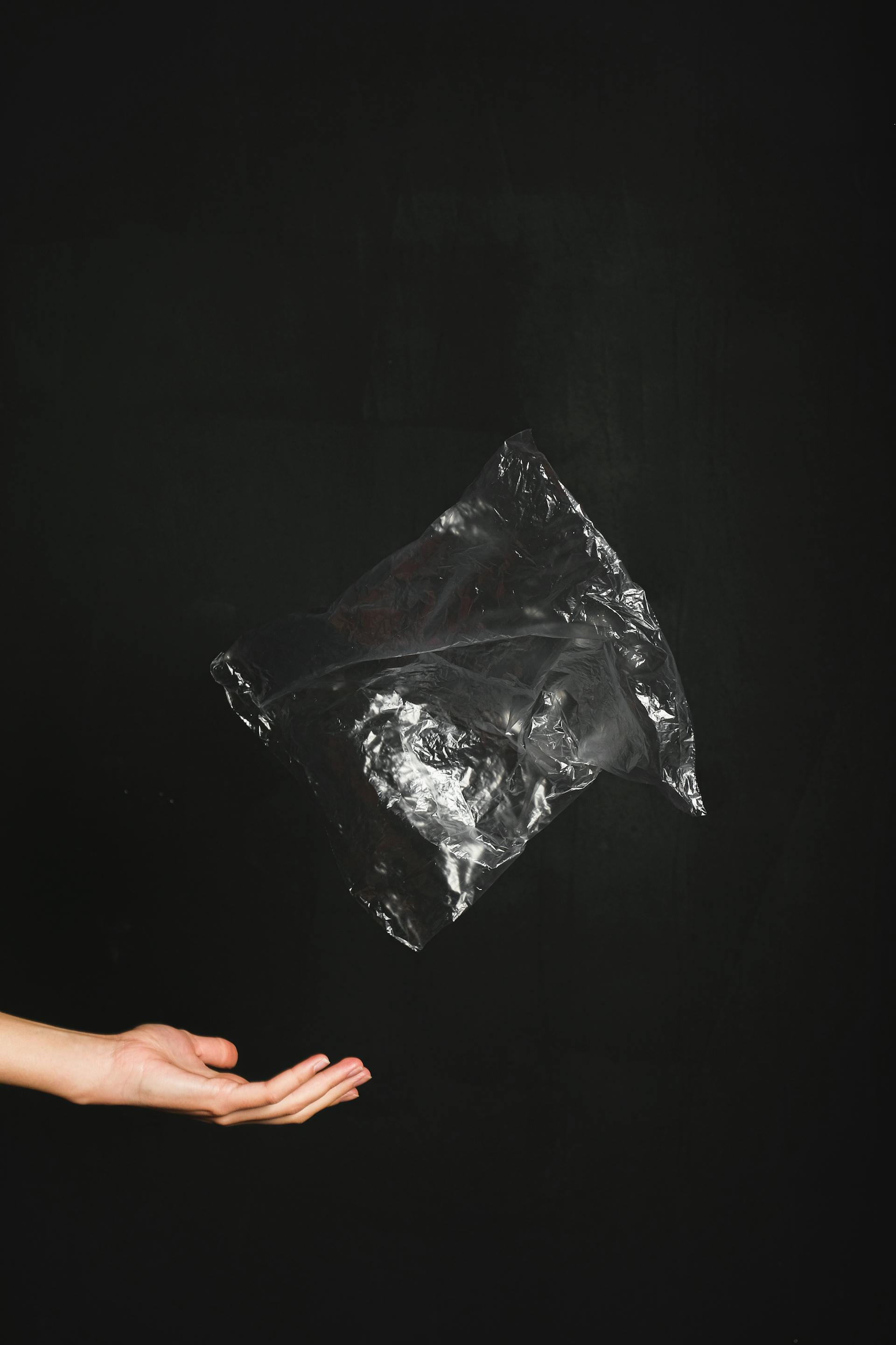 Primer plano de una mano lanzando una bolsa de plástico negra | Fuente: Pexels