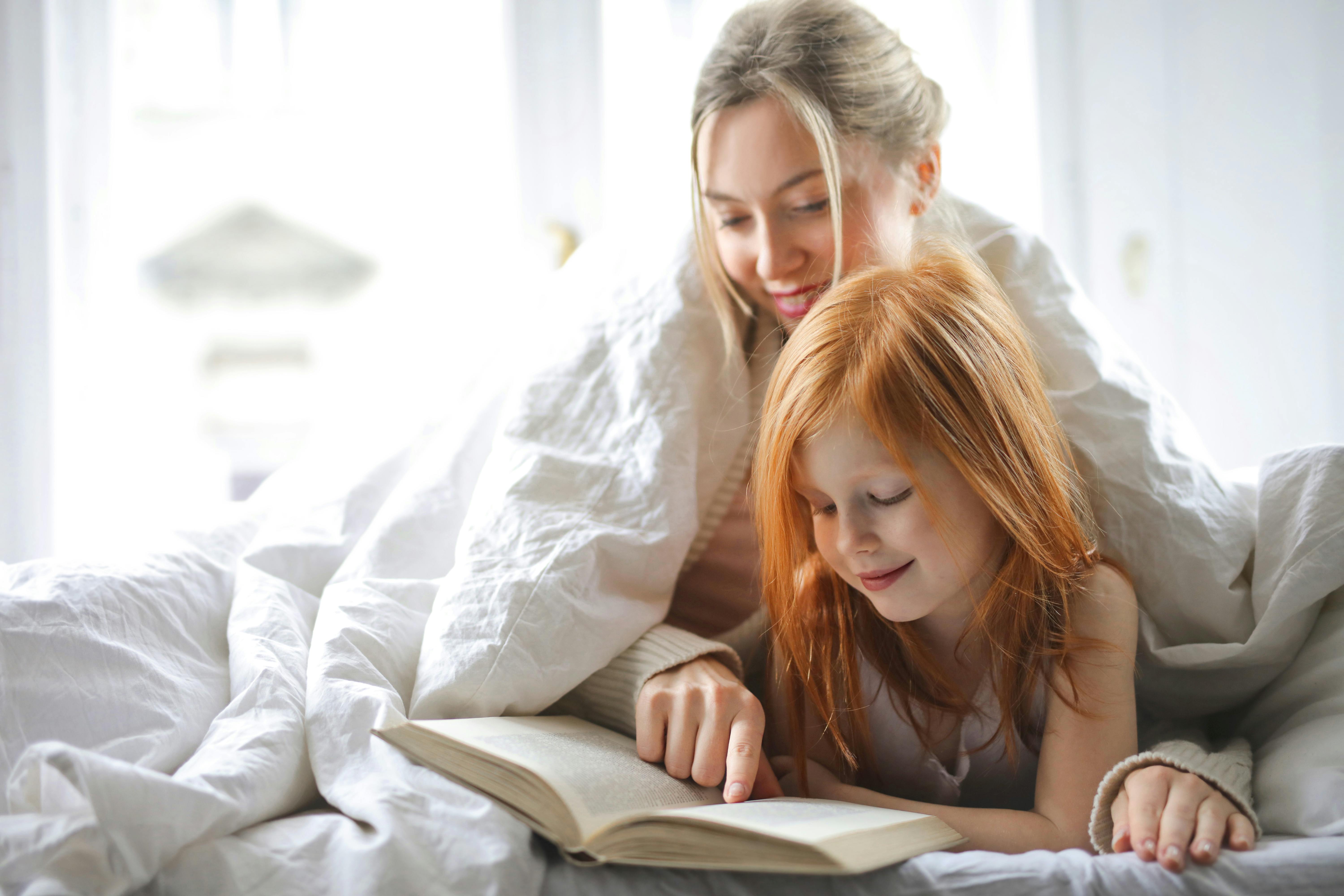 Una madre leyendo un cuento a su hija | Fuente: Pexels