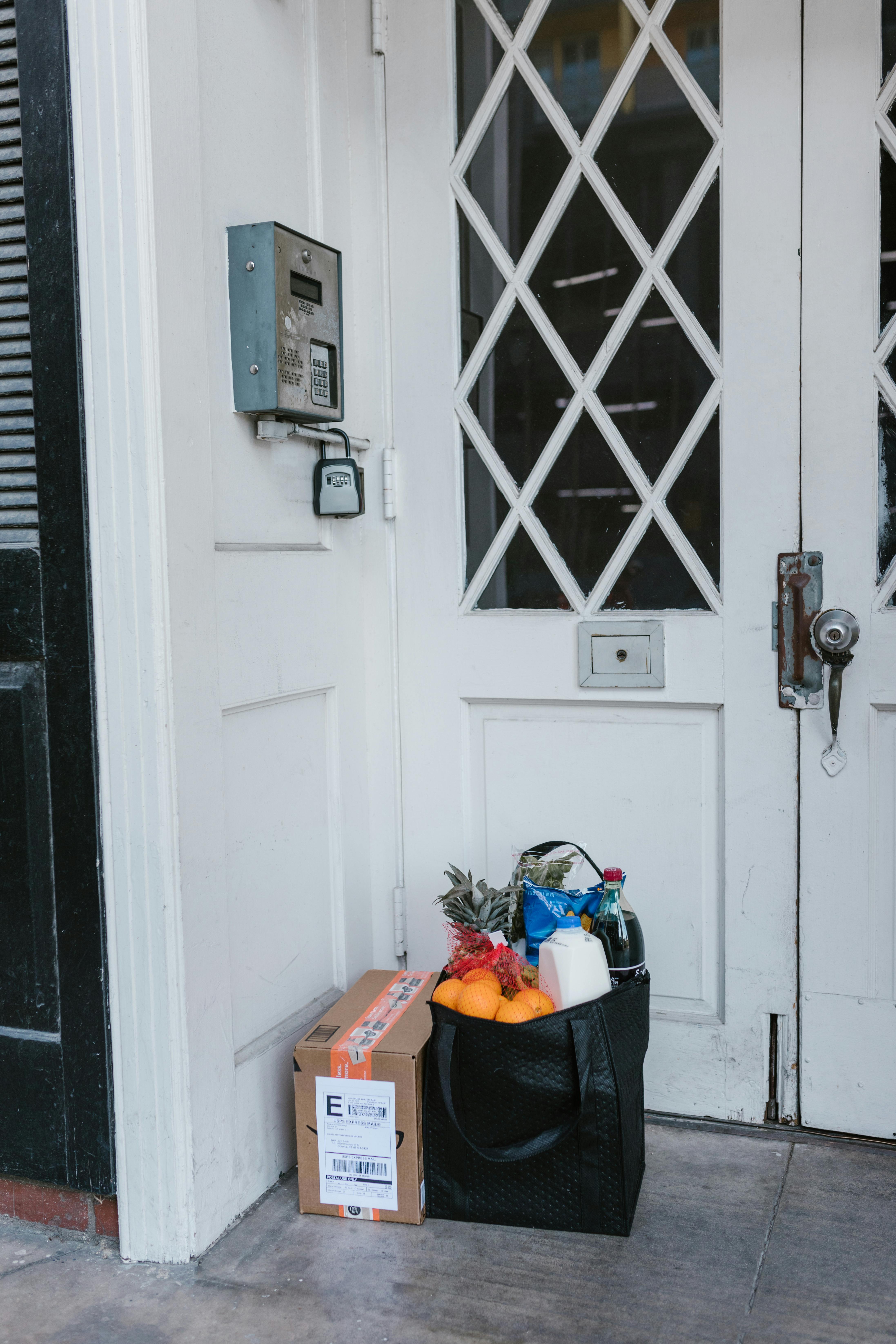Una bolsa de la compra y un paquete en la puerta de una casa | Fuente: Pexels