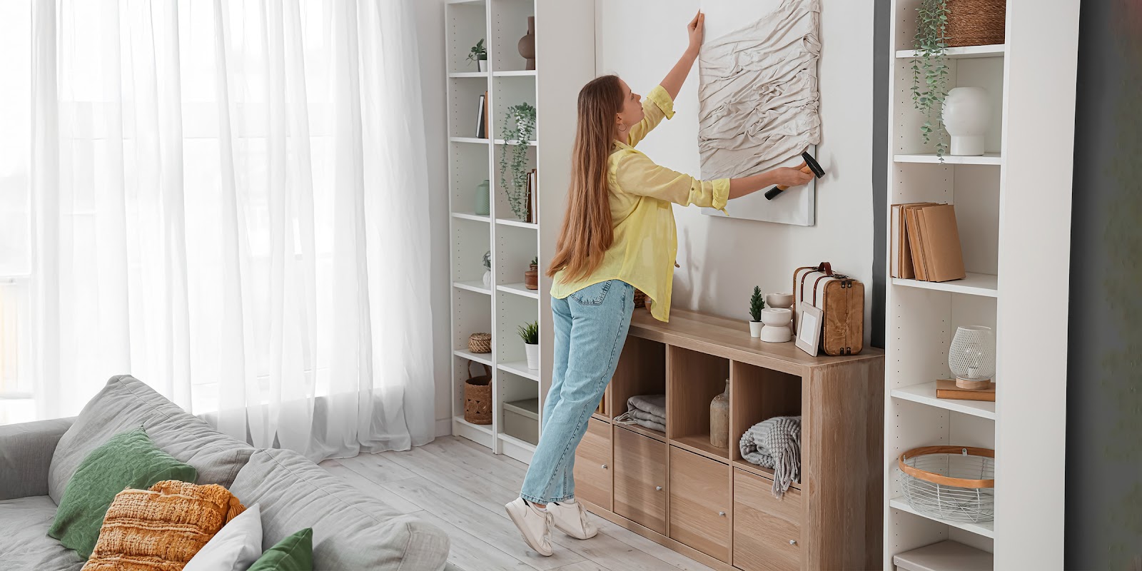 Una mujer colgando un cuadro | Fuente: Shutterstock