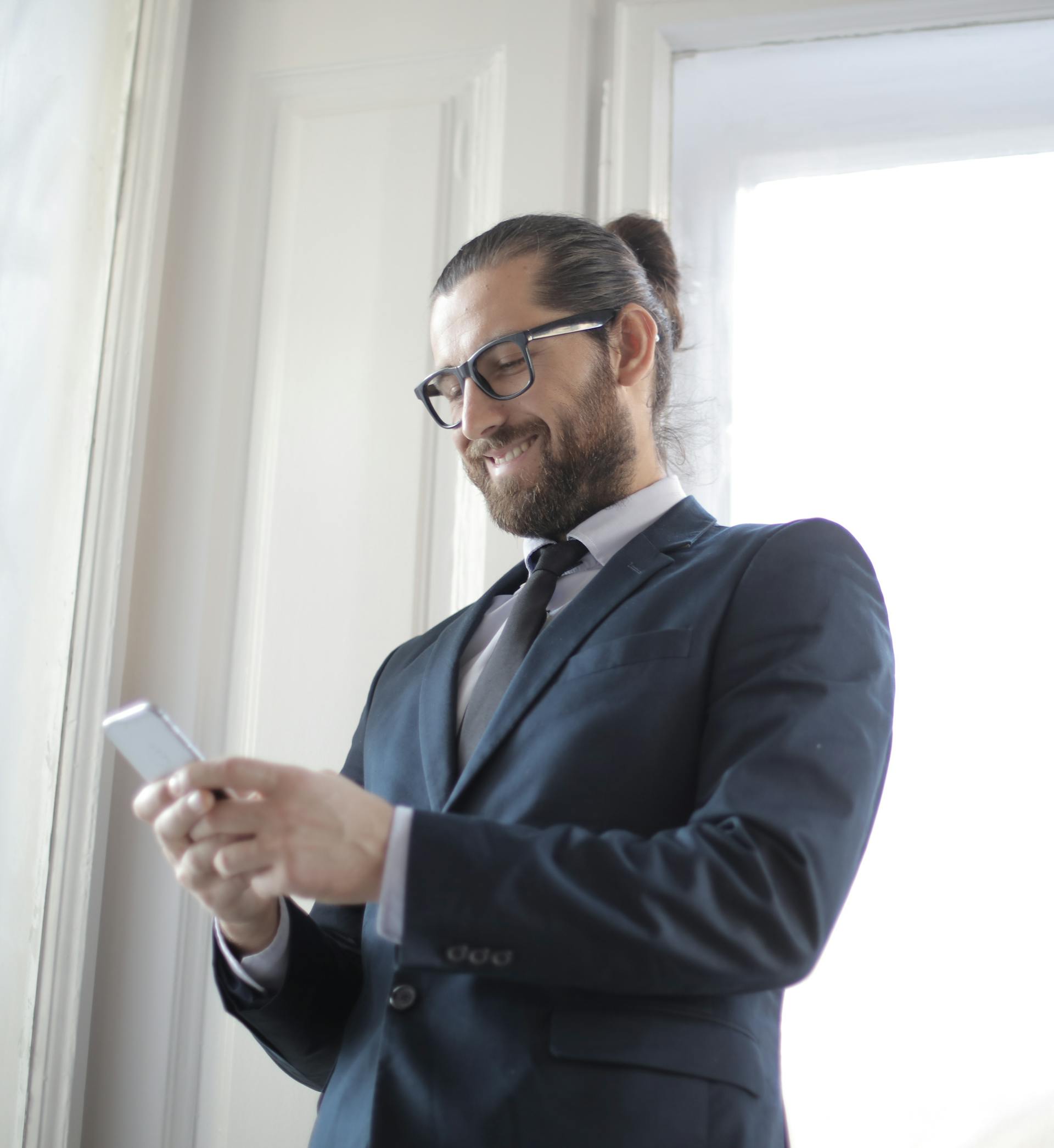 Un hombre sonriendo a su teléfono | Fuente: Pexels