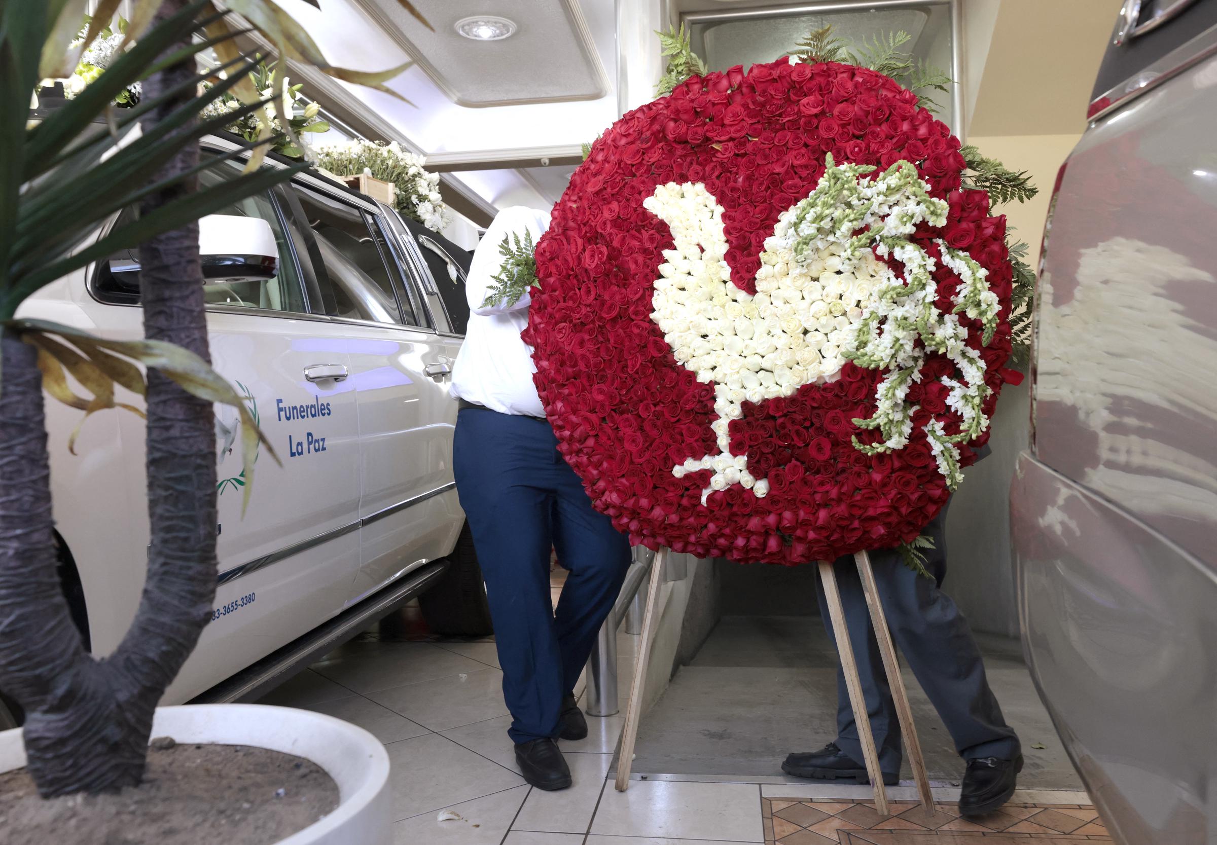 Empleados de la funeraria colocan una corona floral en la funeraria La Paz, durante el velorio de Nemesio "El Mencho" Oseguera en Guadalajara, estado de Jalisco, México, el 2 de marzo de 2026. | Fuente: Getty Images.