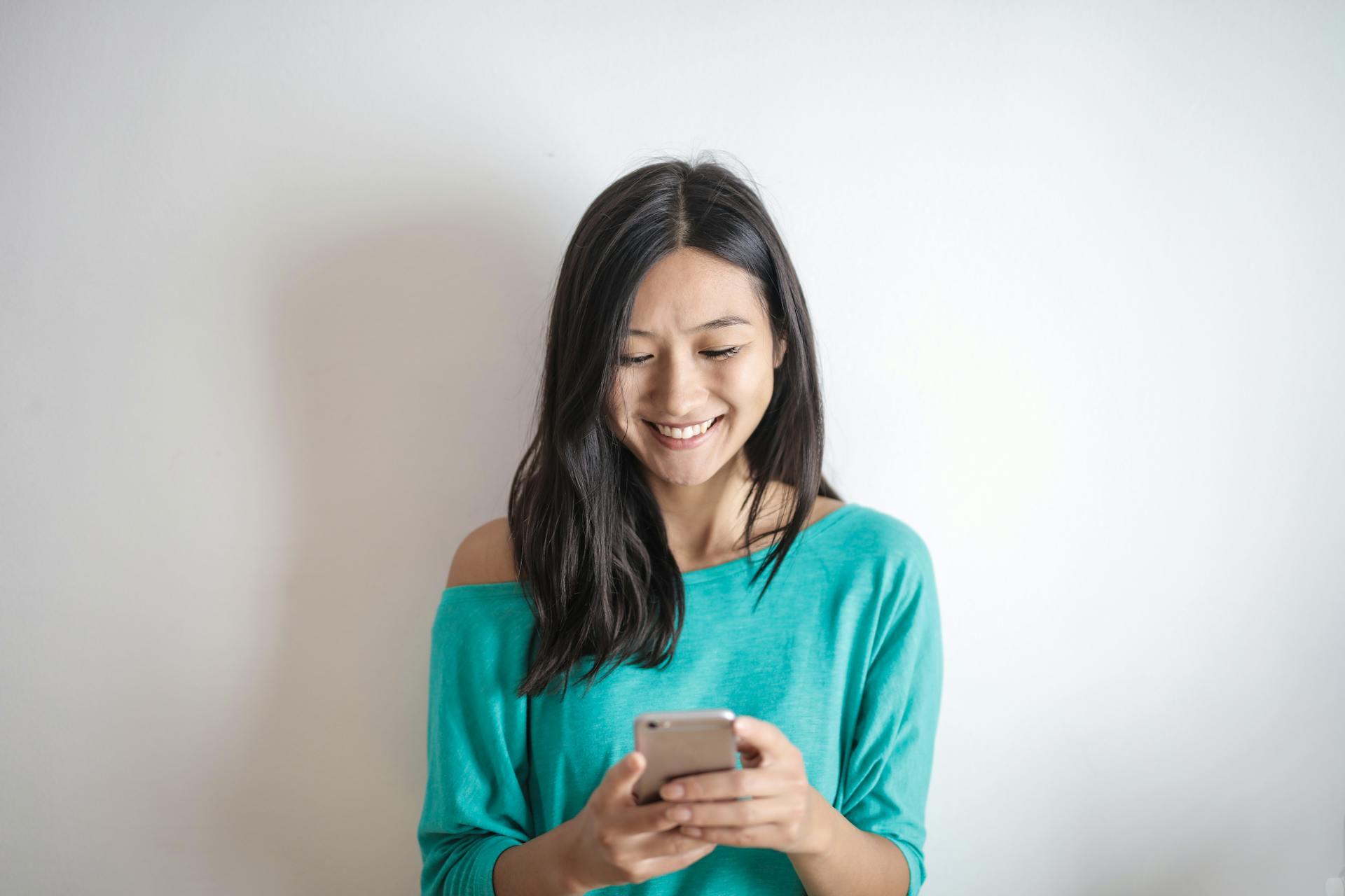 Una mujer sonriendo a su teléfono | Fuente: Pexels