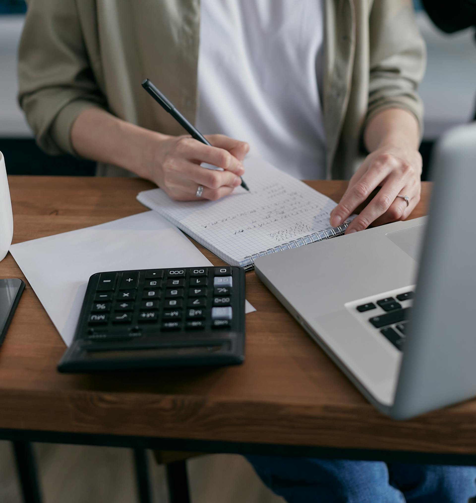 Primer plano de una mujer haciendo cálculos en un bloc de notas | Fuente: Pexels