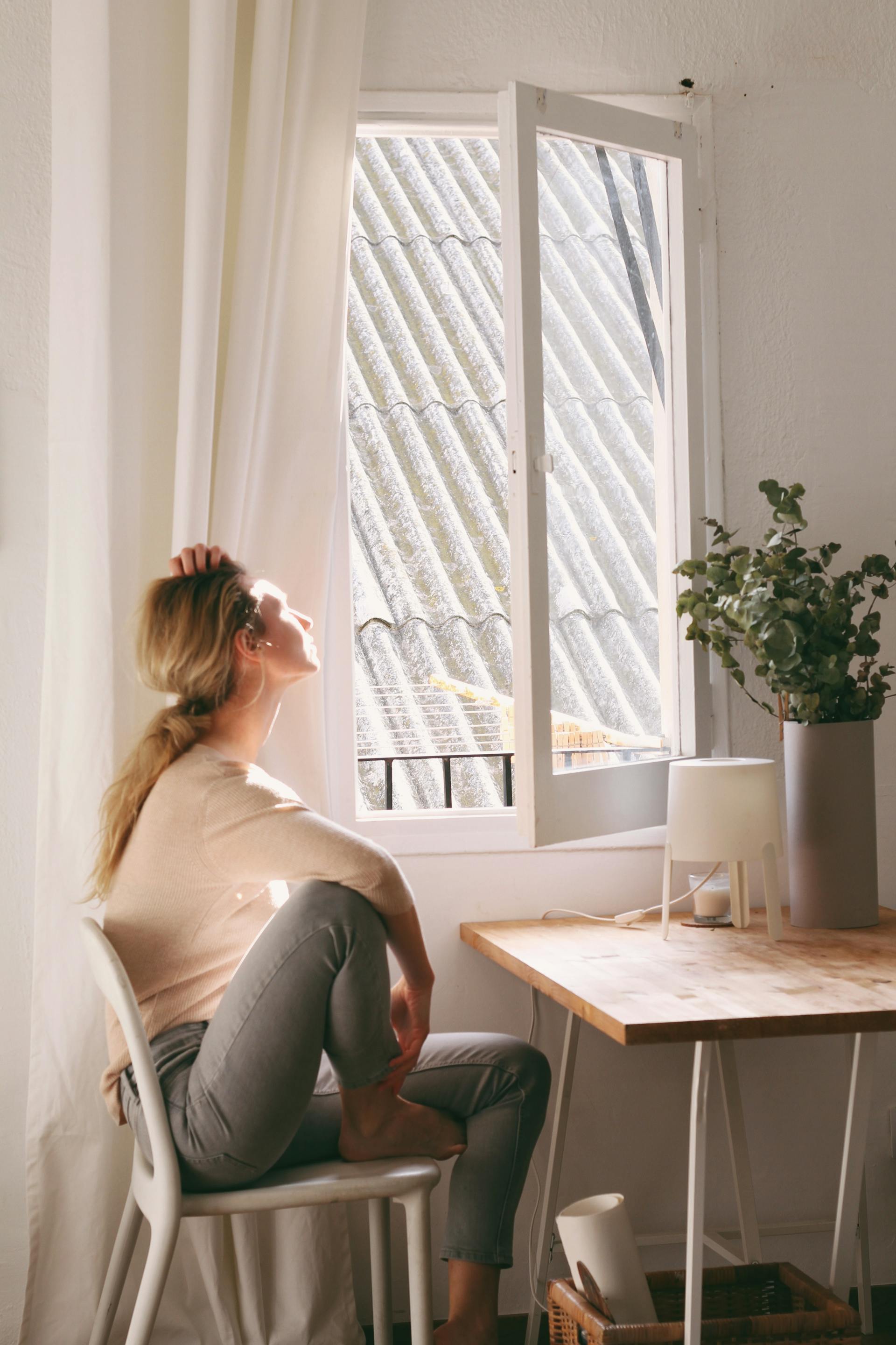 Una mujer sentada mirando por la ventana | Fuente: Pexels