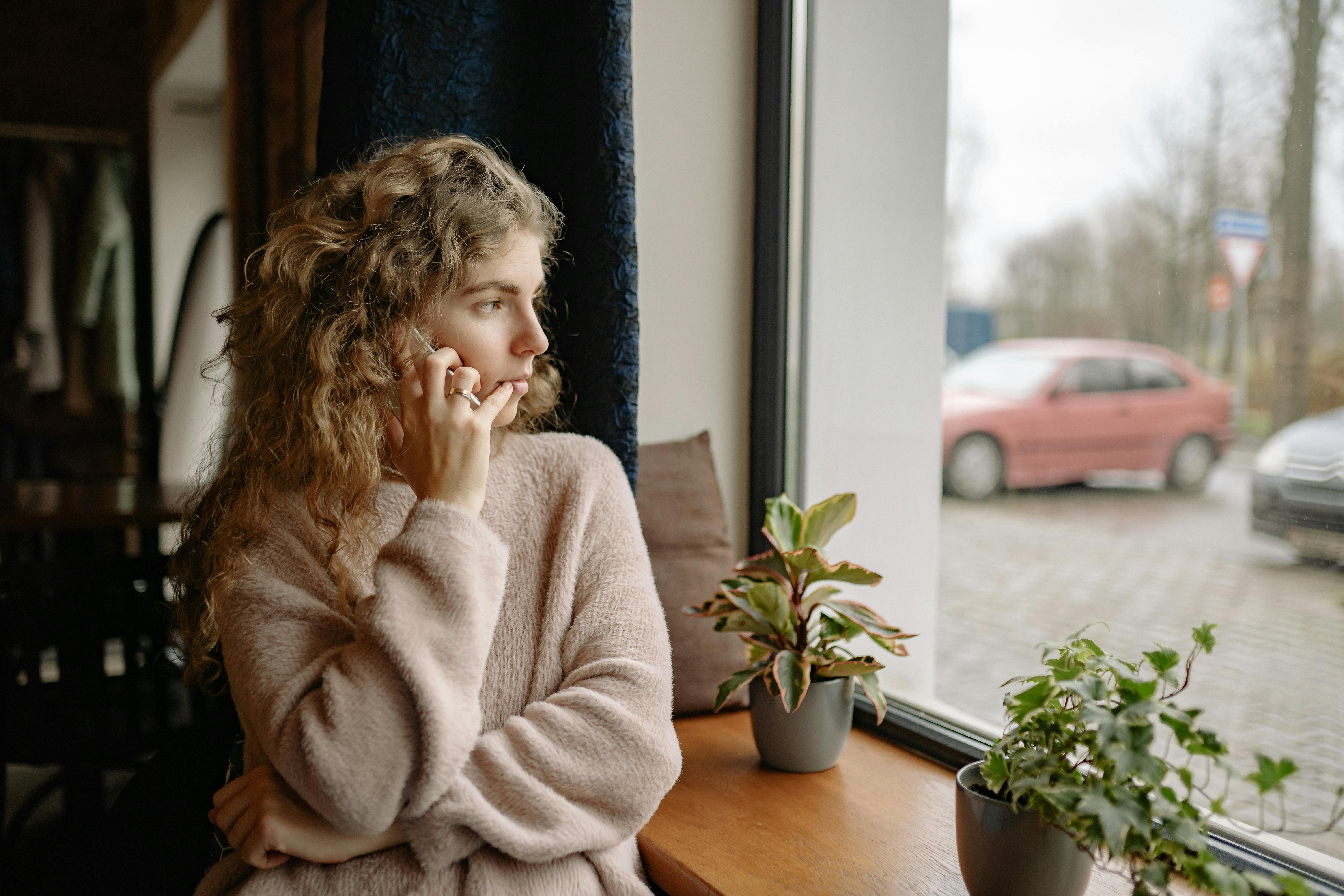 Mujer hablando por teléfono mientras mira al exterior | Fuente: Pexels
