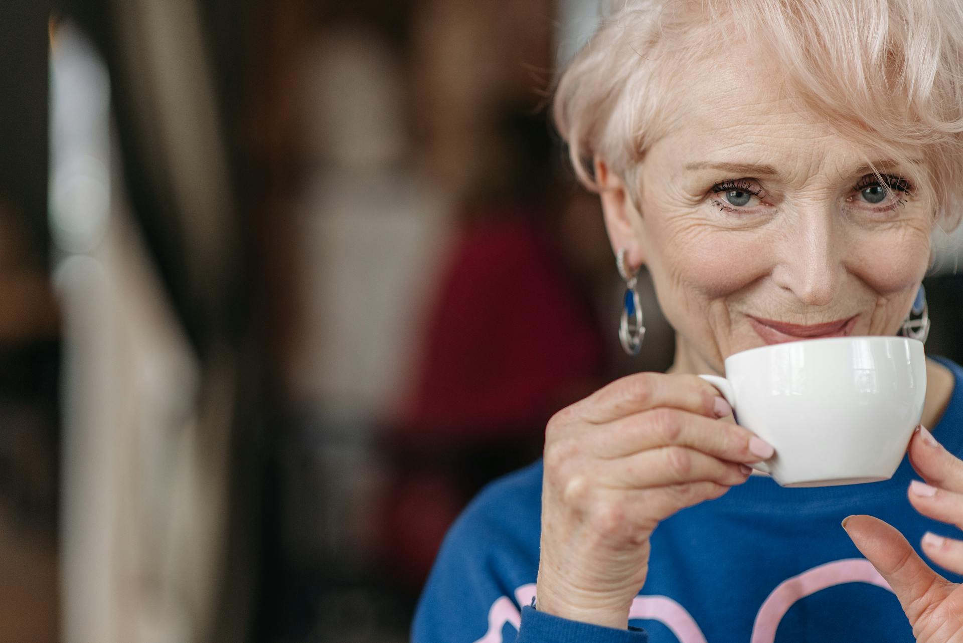Una mujer mayor sonriendo mientras sostiene una taza de café | Fuente: Pexels