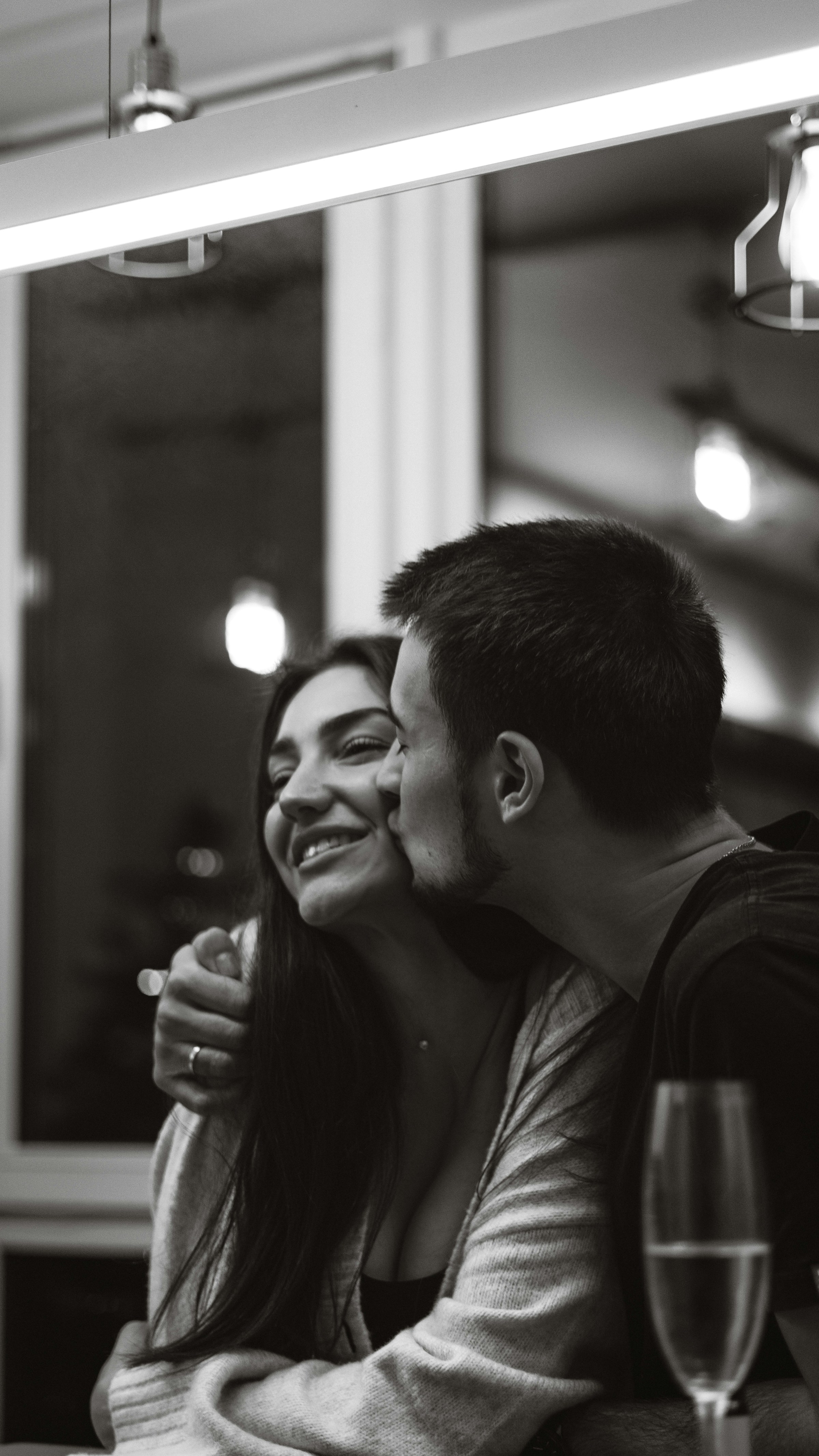 Foto en escala de grises de un hombre besando a una mujer en la mejilla | Fuente: Unsplash