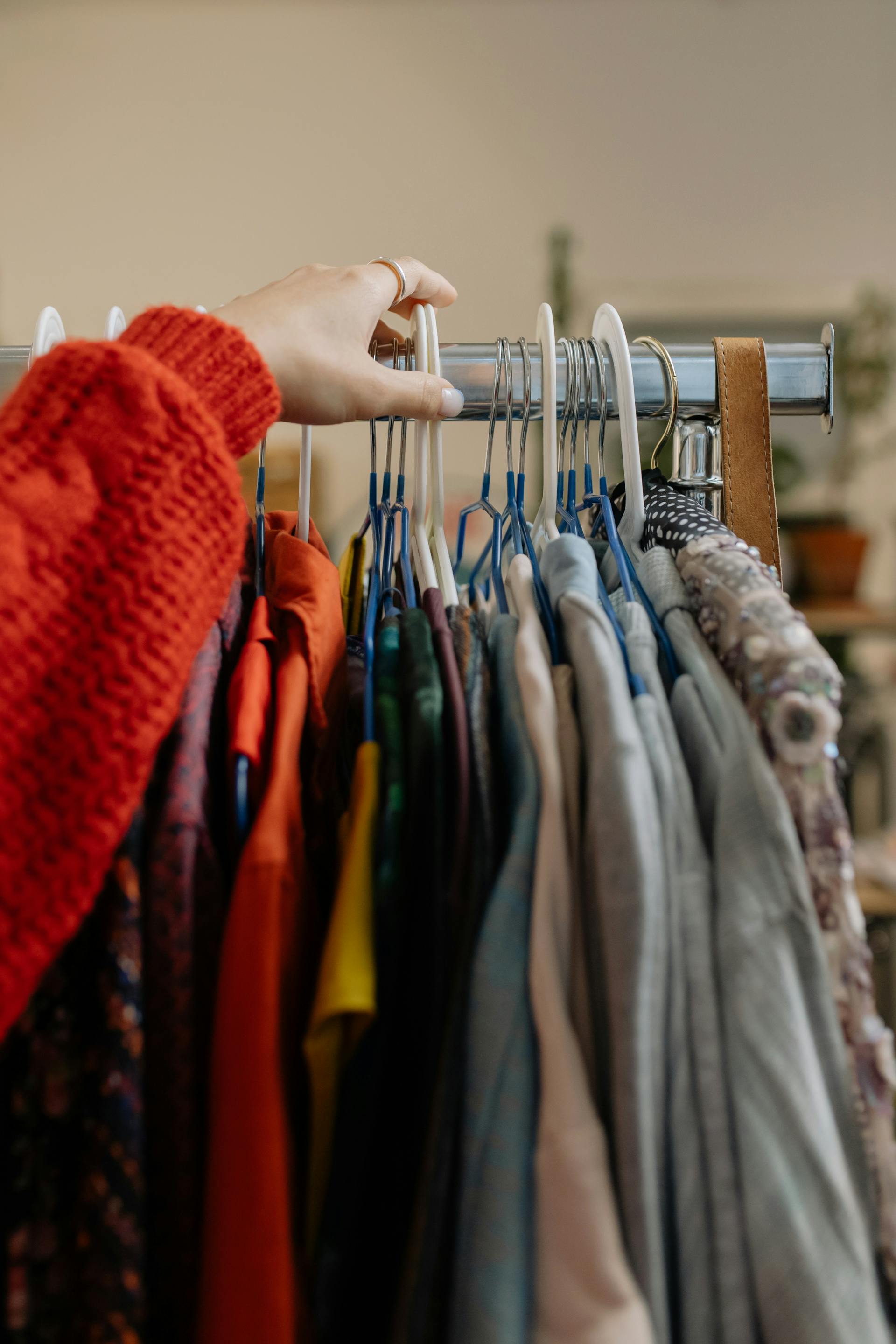 Primer plano de una persona tocando la ropa colgada en una tienda | Fuente: Pexels