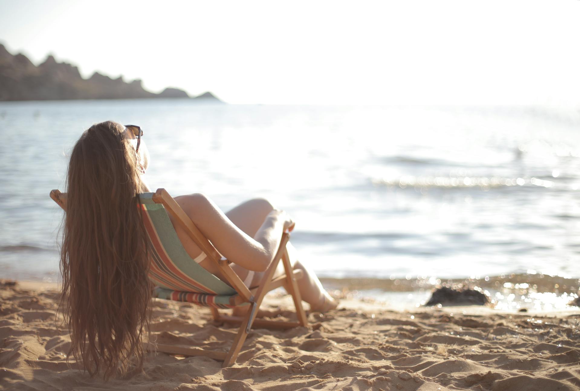 Una mujer en bañador reclinada en una silla de playa | Fuente: Pexels