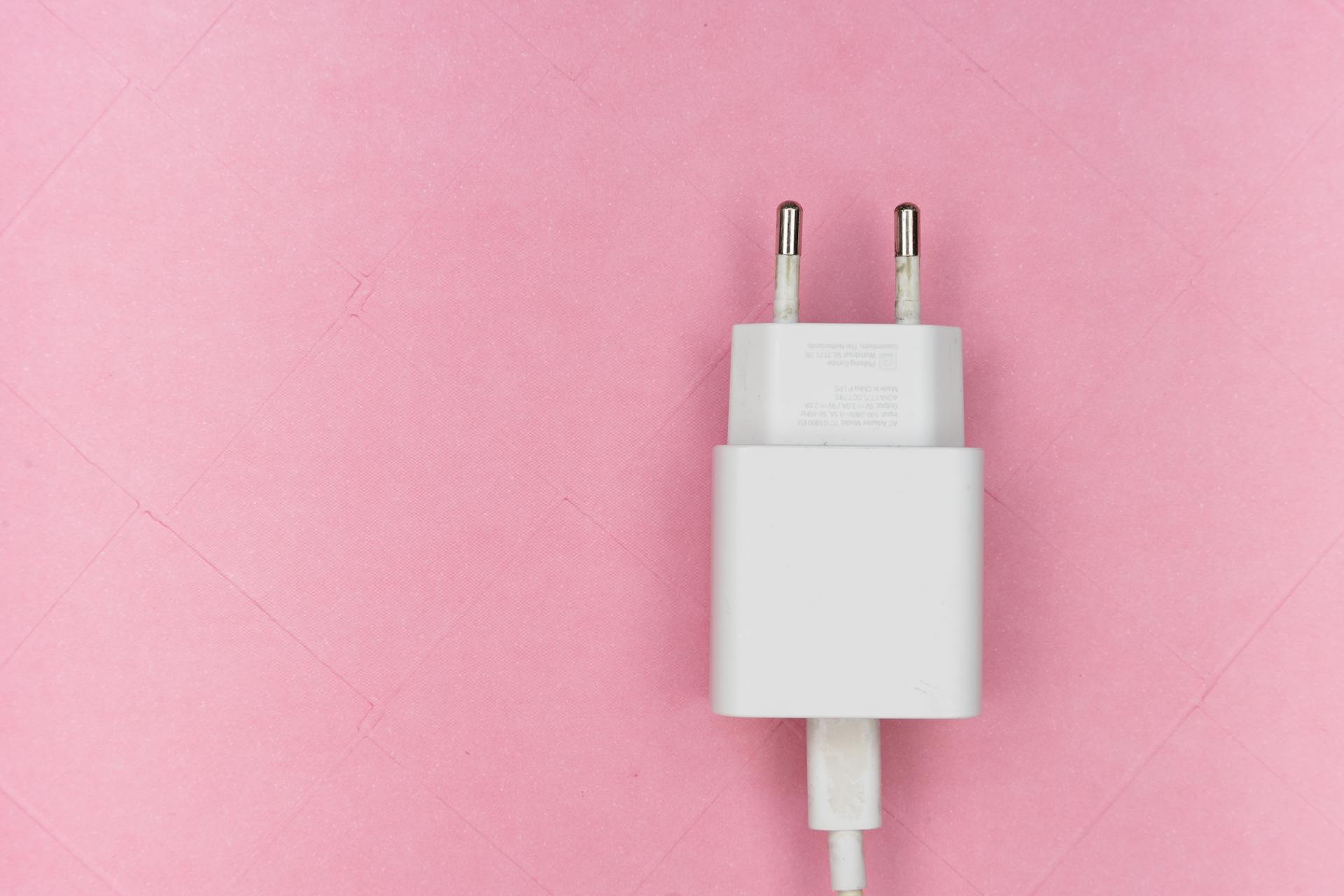 Un adaptador móvil sobre una superficie rosa | Fuente: Pexels